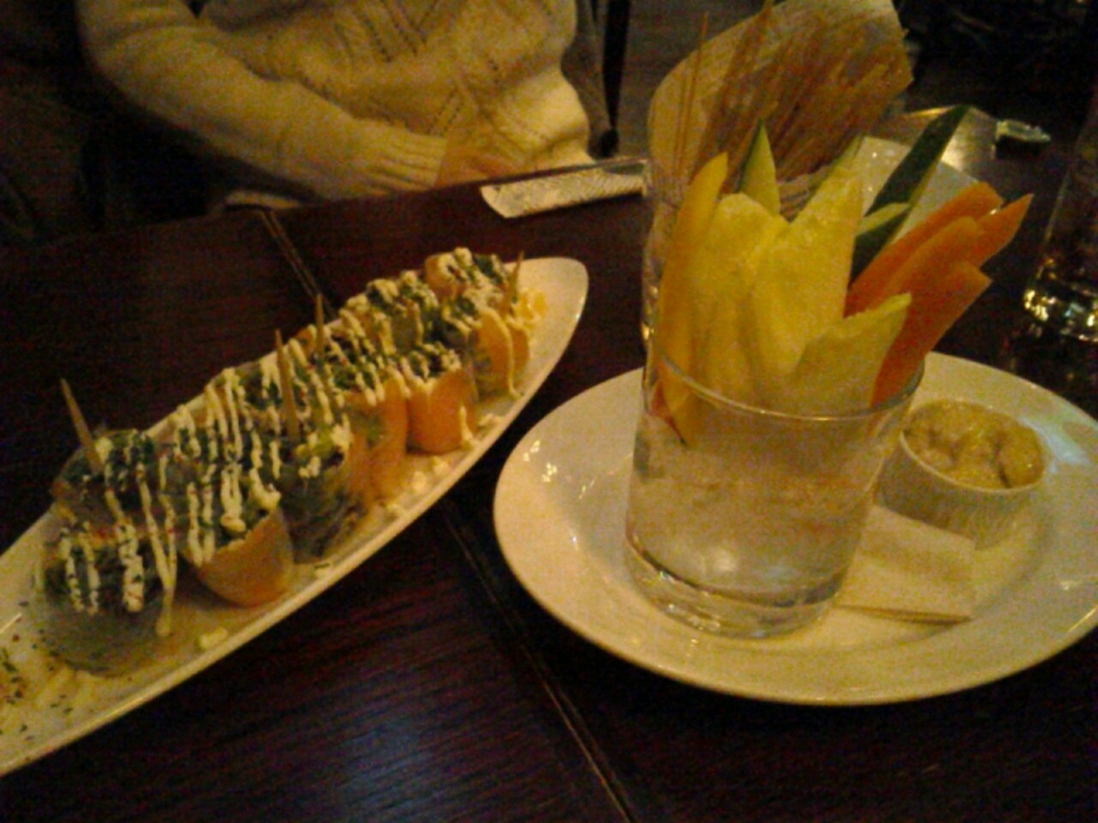 Plato de sushi verde y naranja junto a un cóctel de frutas