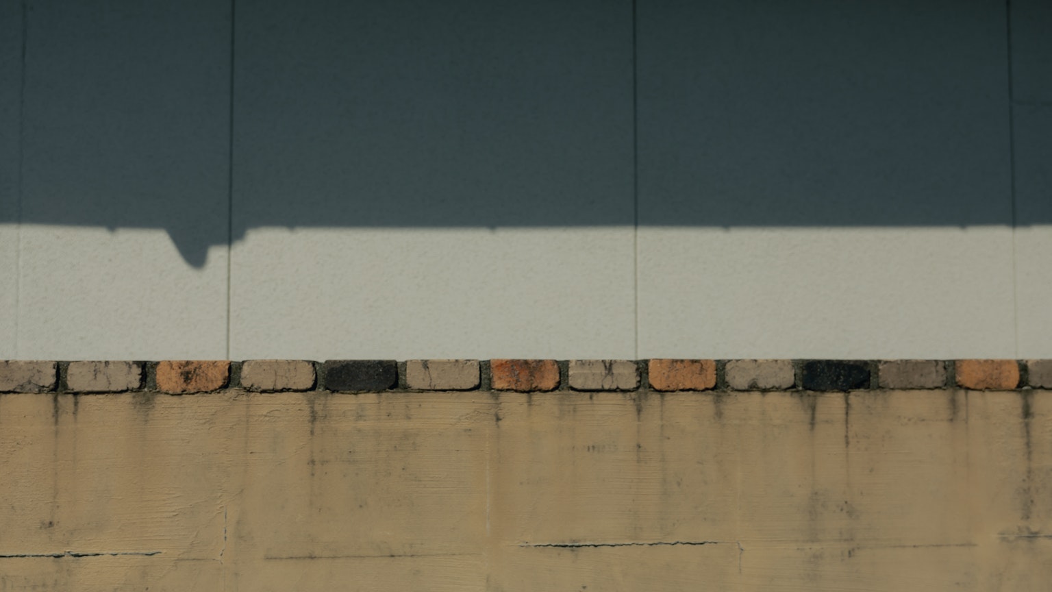 Structure featuring a blue wall with a white stripe and a brick foundation at the bottom