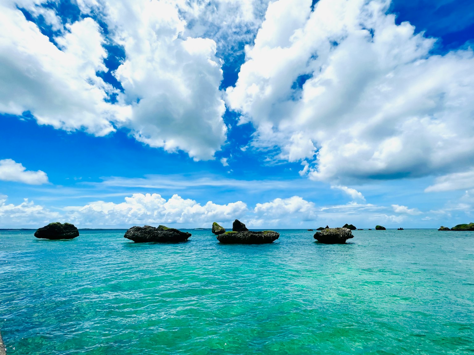美麗的藍色海洋和白色雲朵的風景，岩石點綴其間