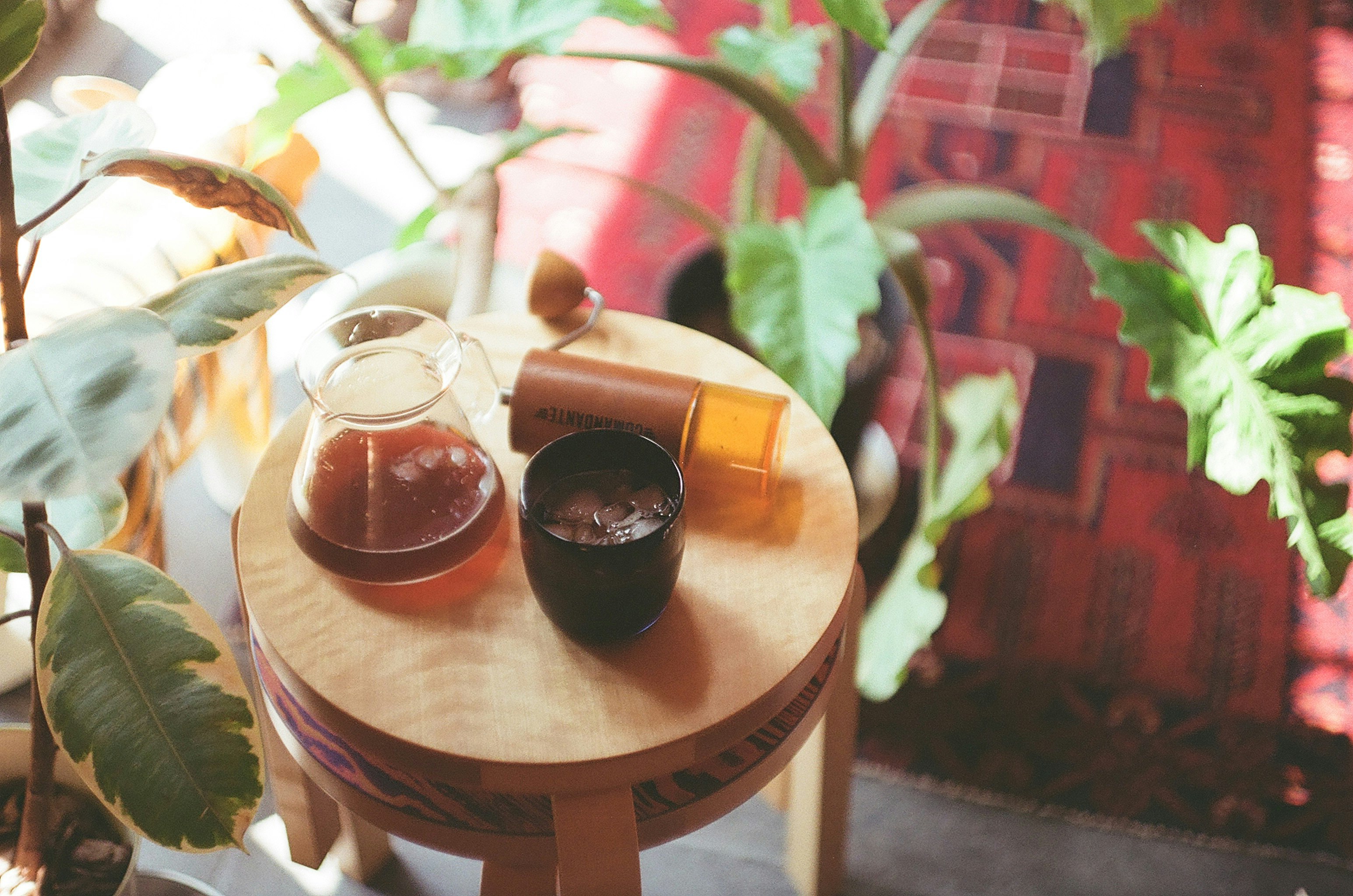 tasses et boissons sur une table ronde en bois avec des plantes en pot dans un café