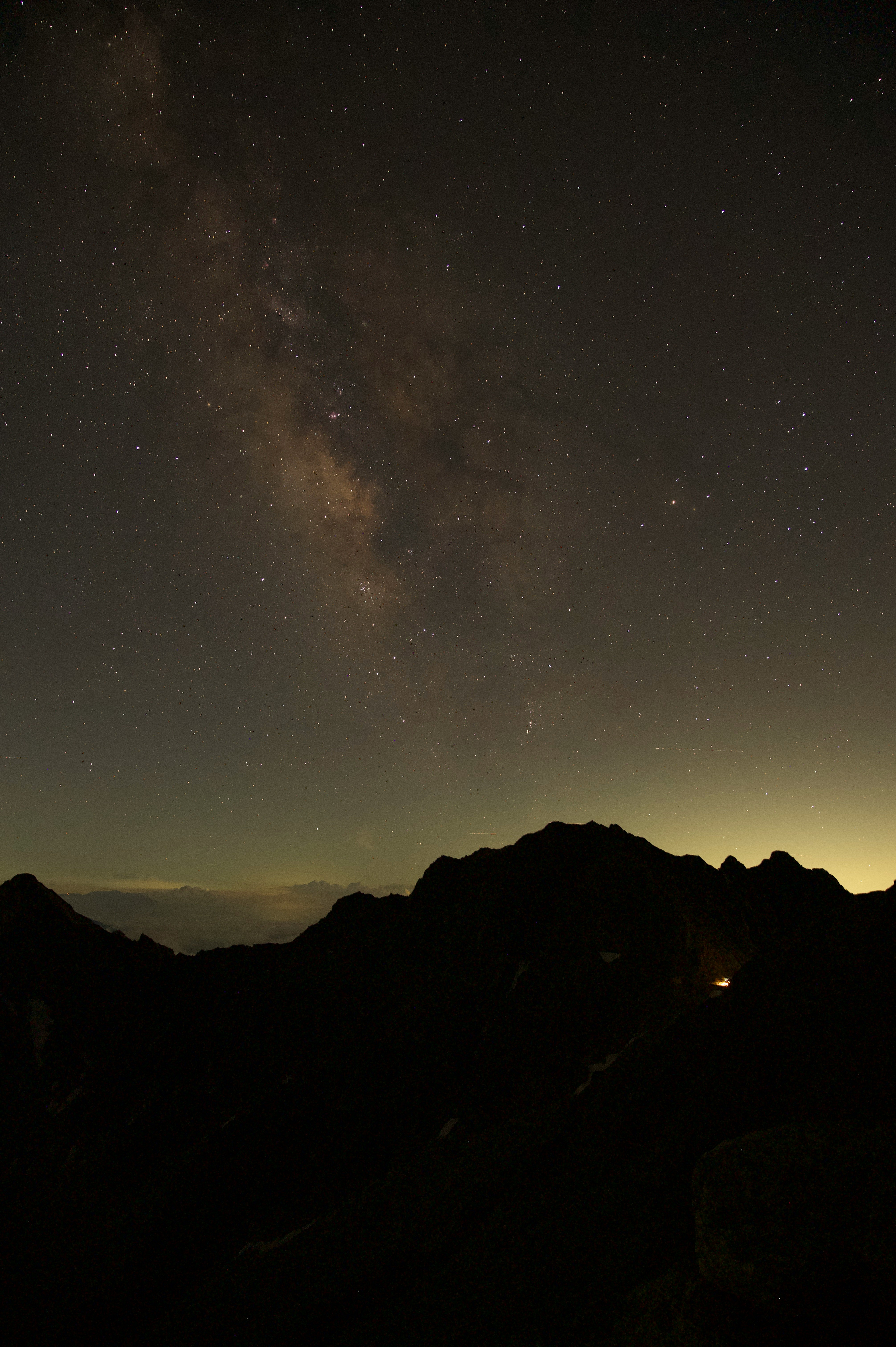 山稜のシルエットと天の川が広がる夜空の風景