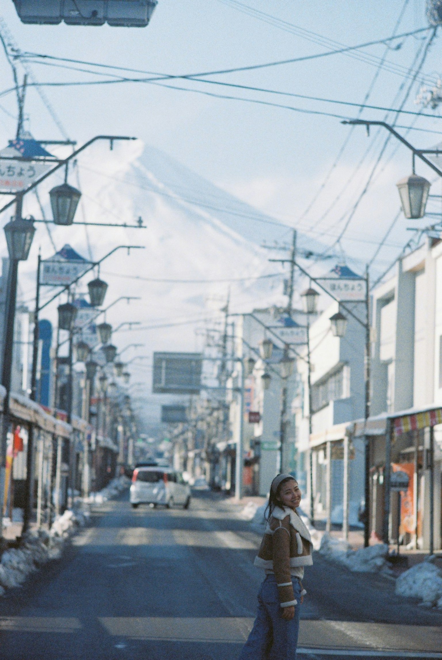 Una scena di strada tranquilla con il monte Fuji sullo sfondo una persona in piedi al centro della strada
