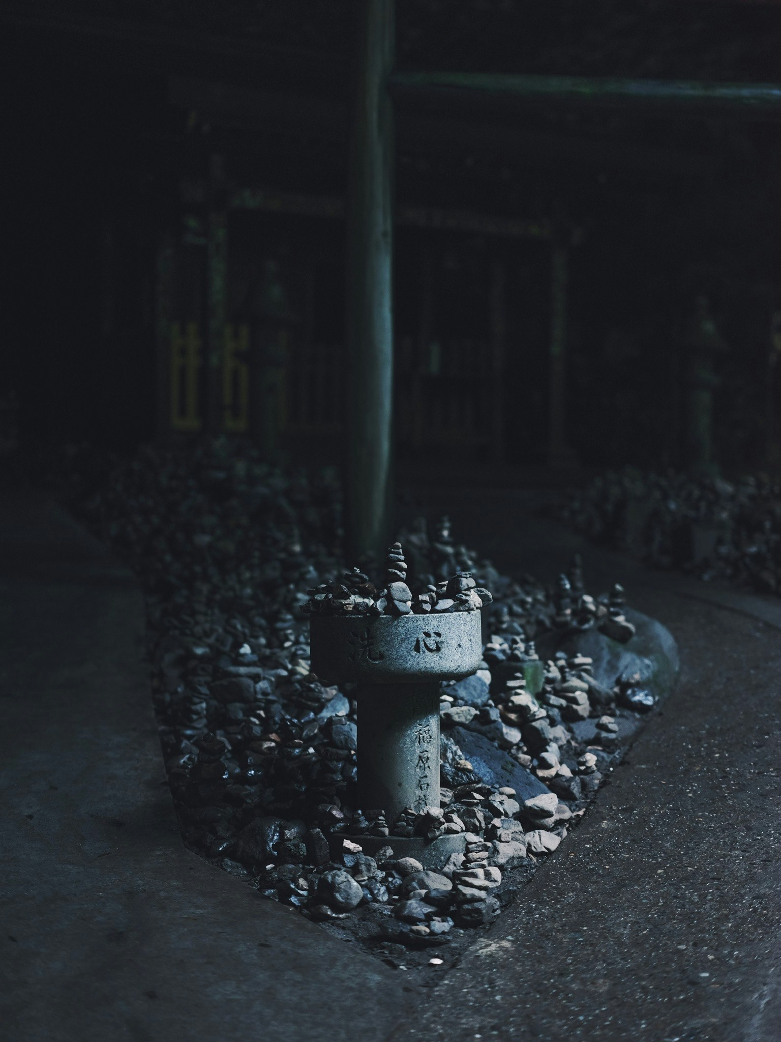A white faucet in a dark space surrounded by a pile of stones