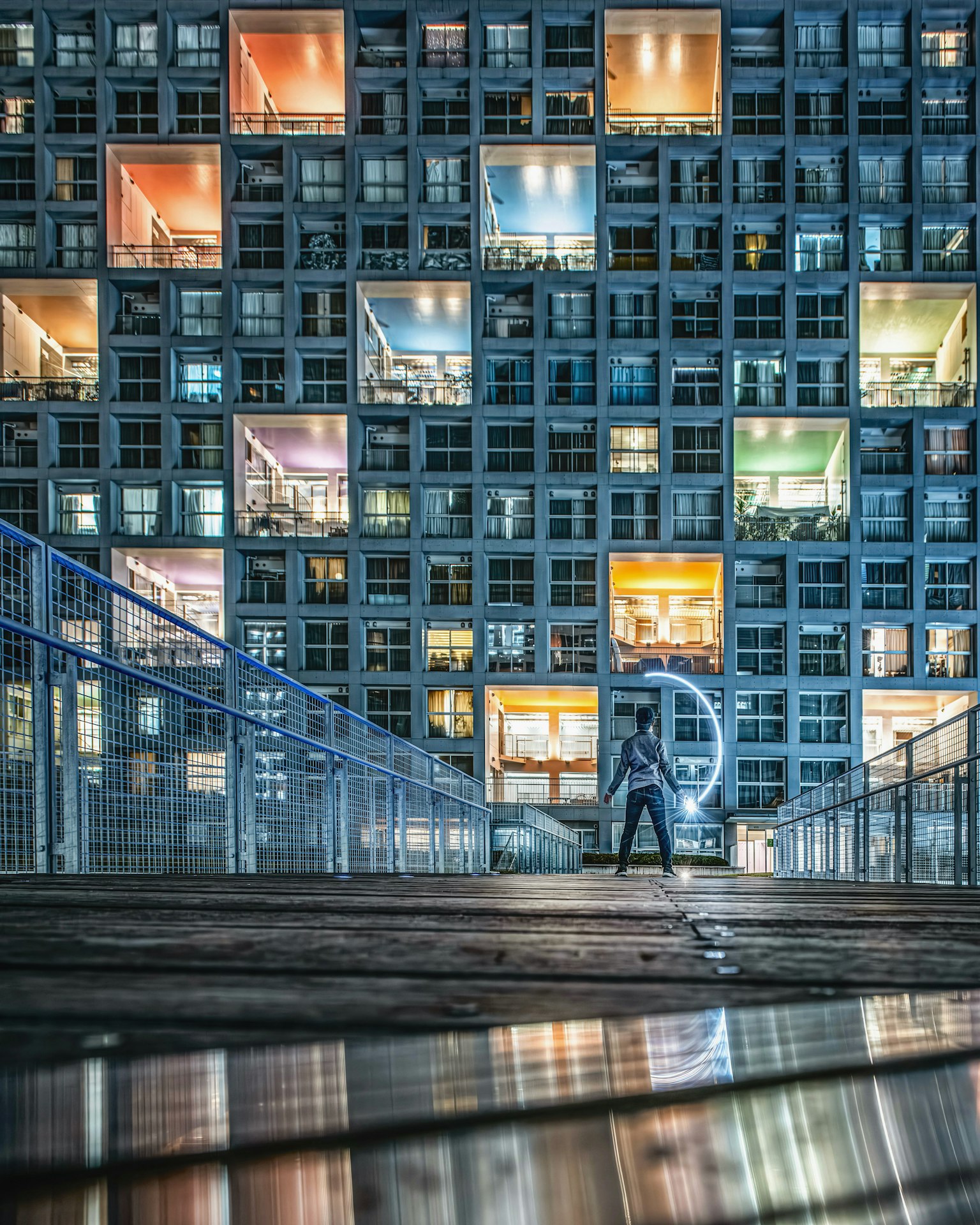 Eine Person steht vor einem modernen Gebäude mit bunten Fenstern in der Nacht