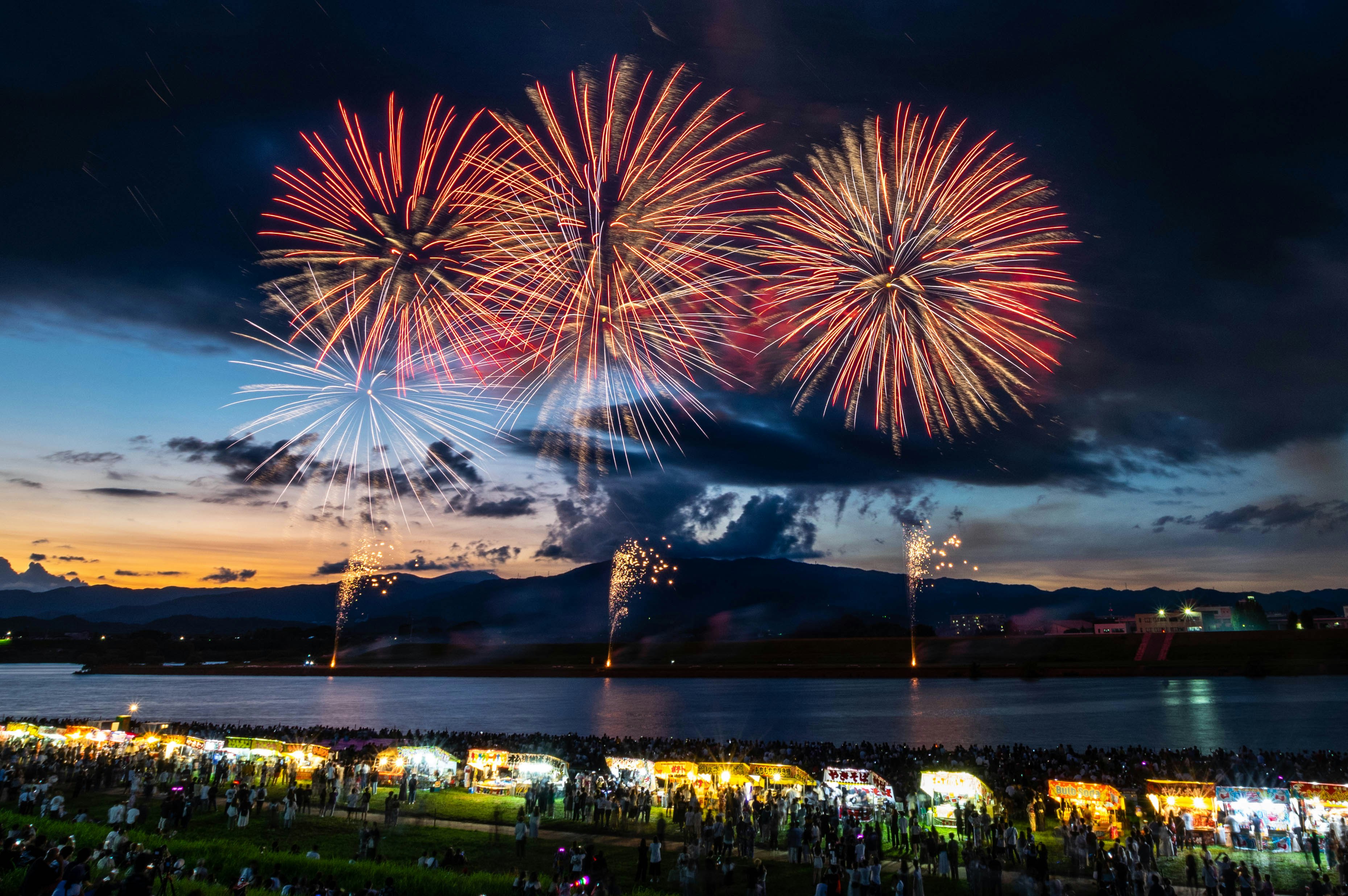 Fuochi d’artificio sopra un lago di notte con luci cittadine