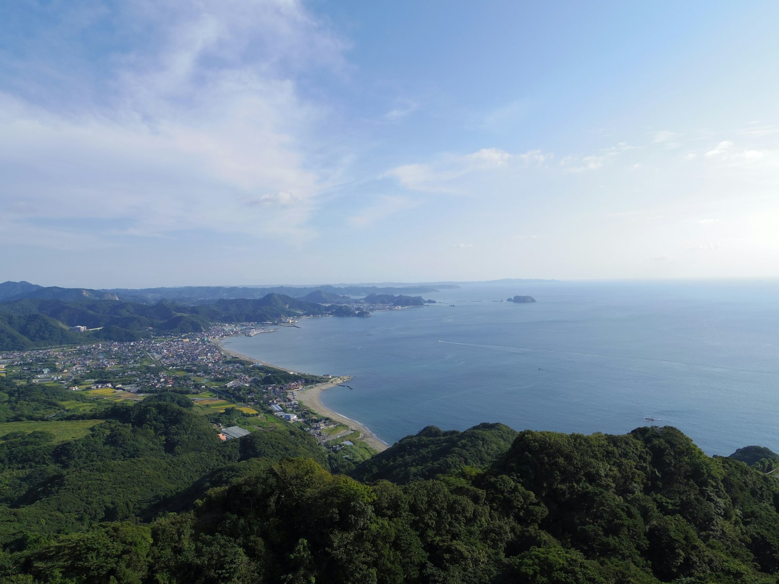 Panoramablick auf den blauen Ozean und grüne Berge unter einem klaren Himmel