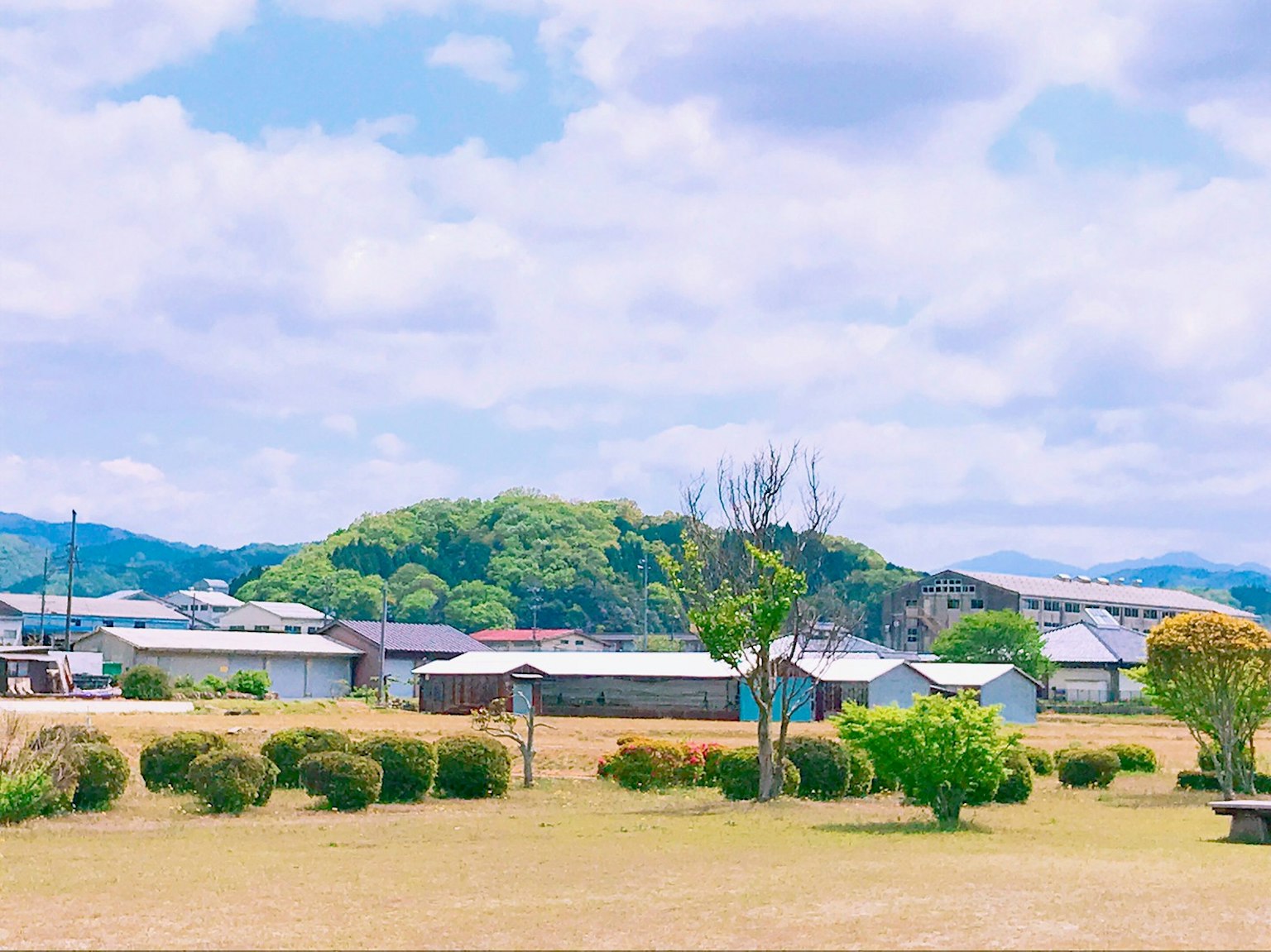 鄉村風景，藍天白雲下有開闊的草地和遠處的山丘