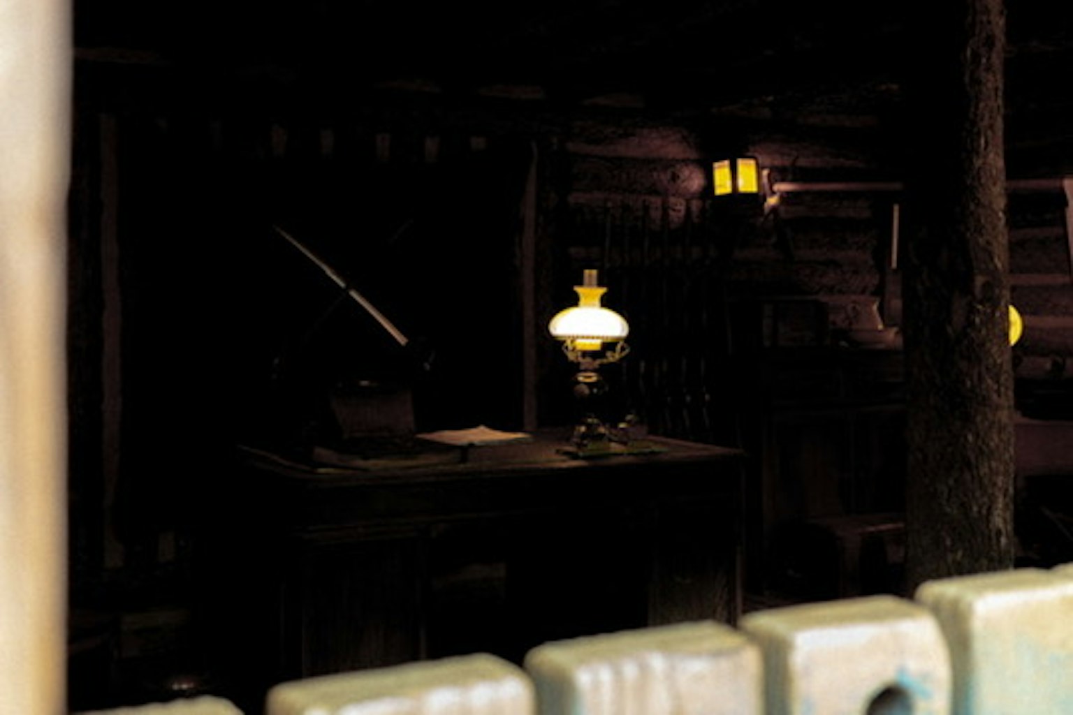 Intérieur faiblement éclairé d'une cabane avec une lampe et une table