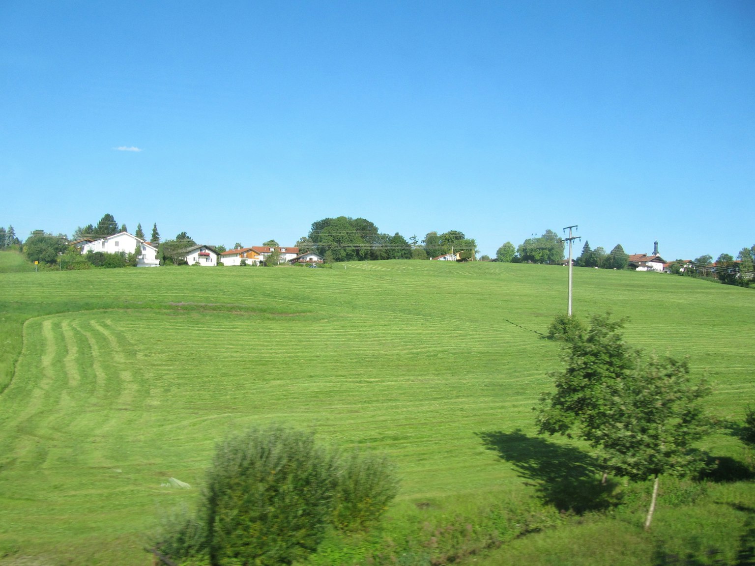 Un paisaje de campos verdes y casas bajo un cielo azul