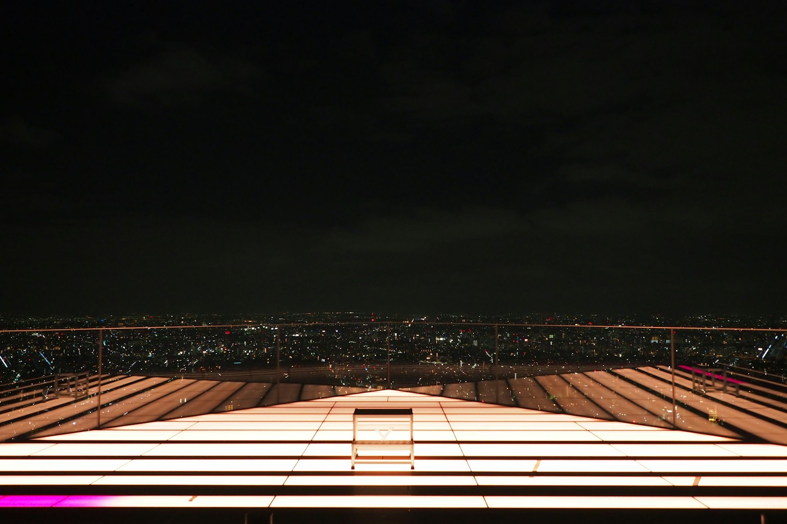 Bright rooftop of an observation deck overlooking a city skyline at night