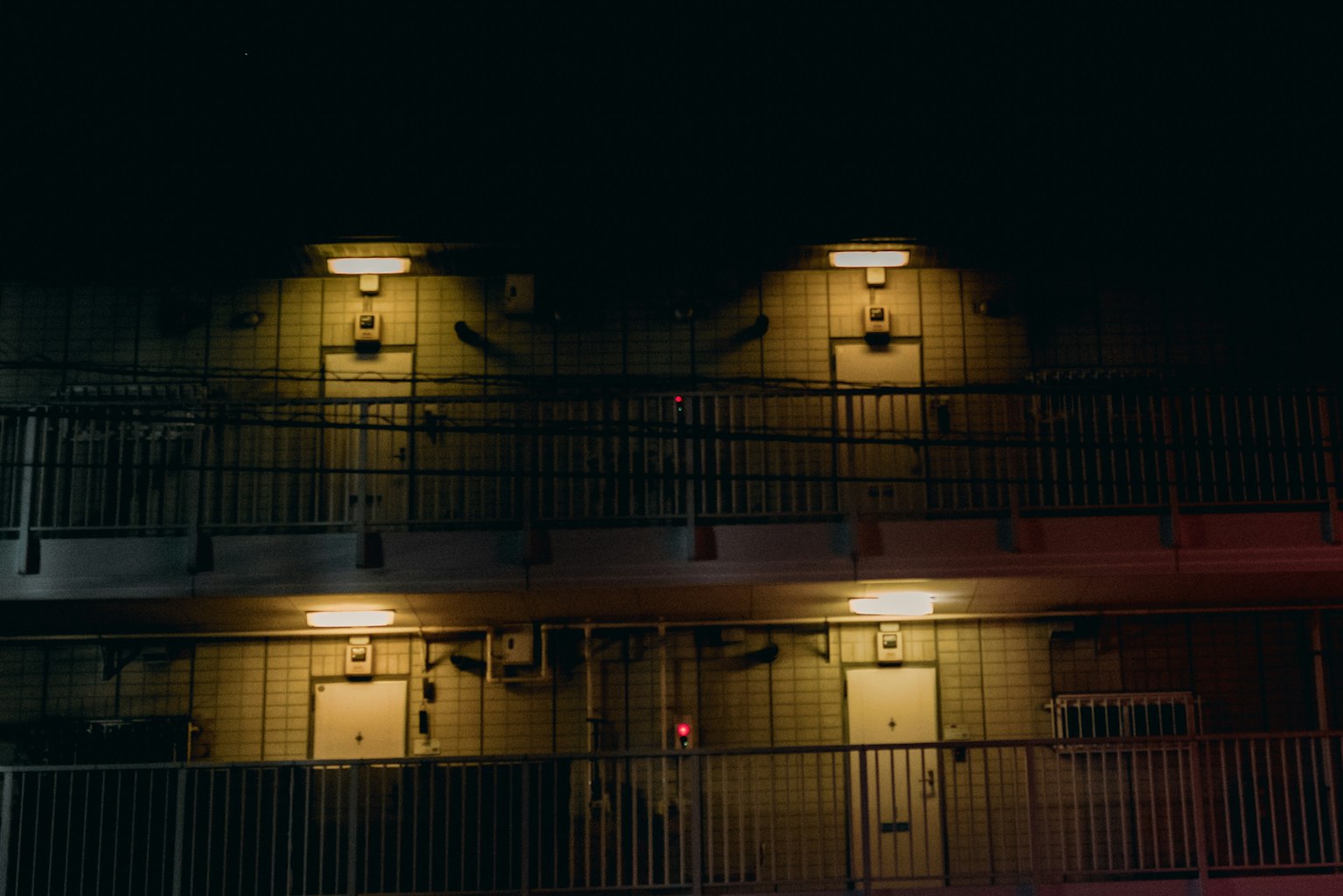 Esterno di un motel illuminato di notte con due piani di balconi e porte