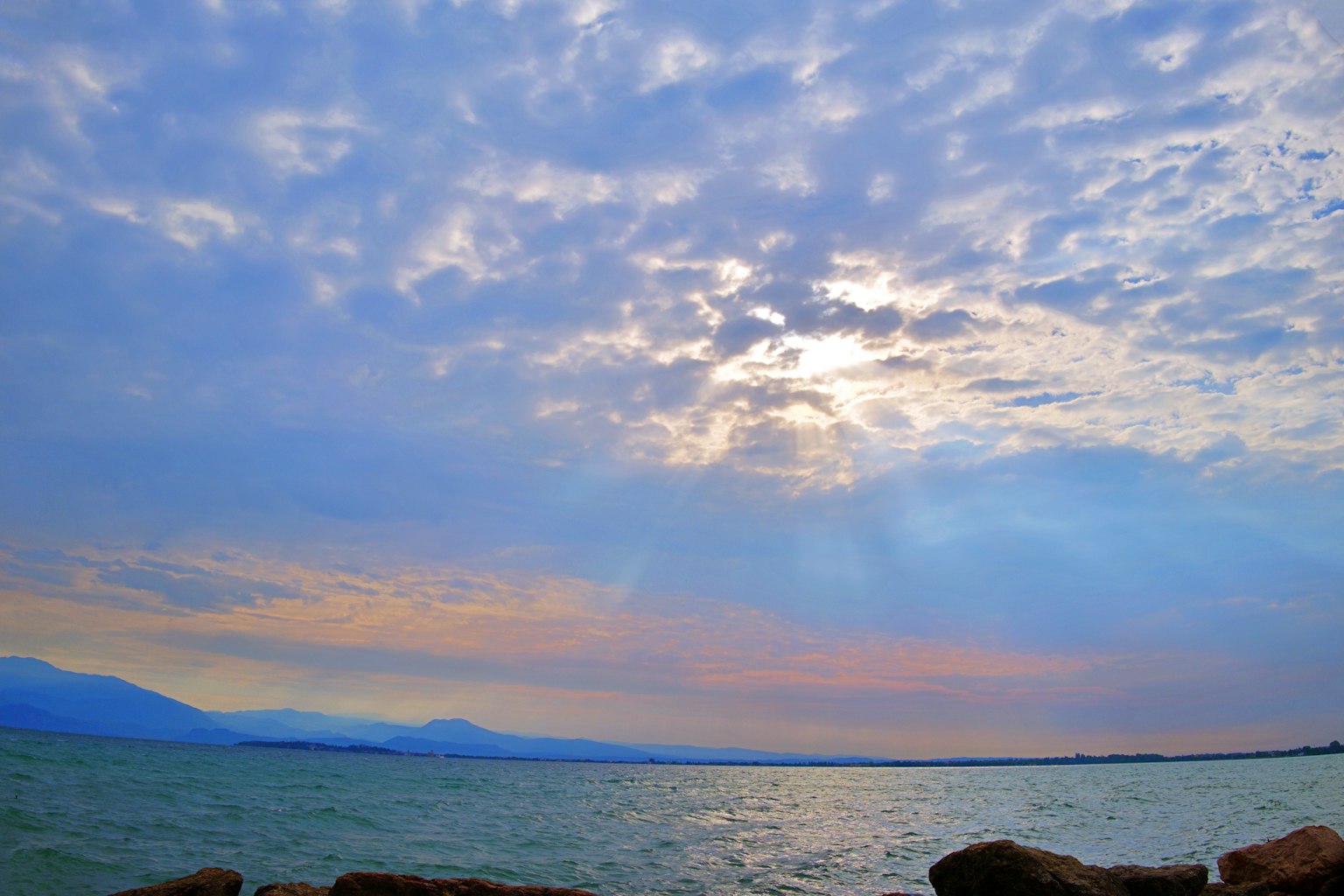 蓝色海洋和多云天空的风景，带有日落色调