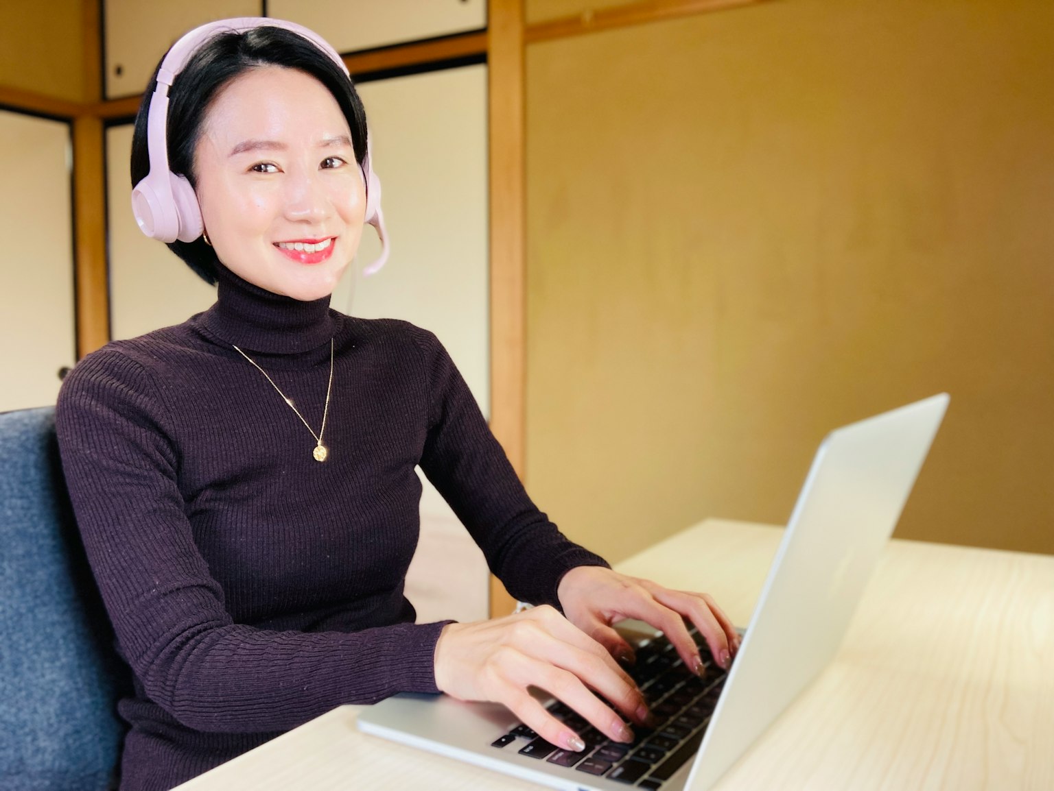 A young woman wearing headphones working on a laptop at a desk