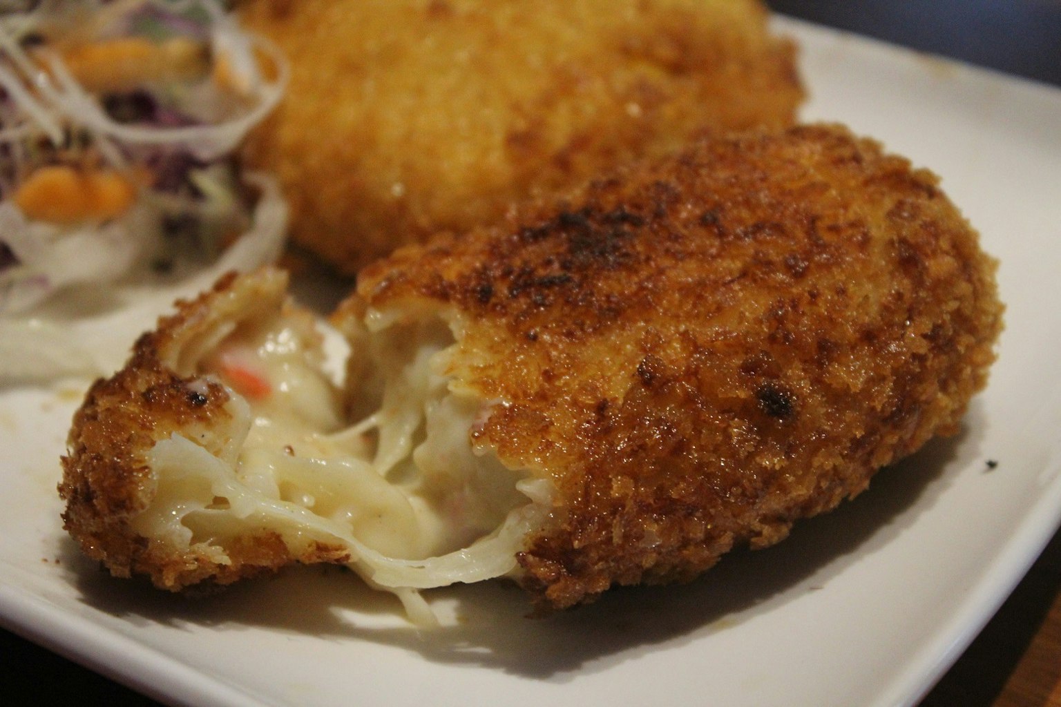 Knusprige Kroketten mit geschmolzenem Käsefüllung serviert mit Salat