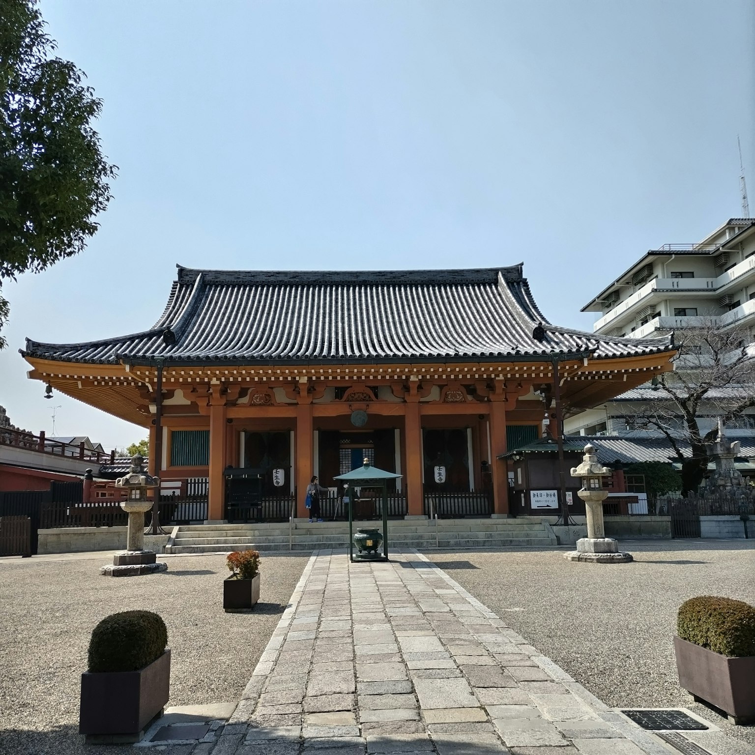 Exterior de un templo japonés tradicional con techo curvado rodeado de jardines y faroles de piedra