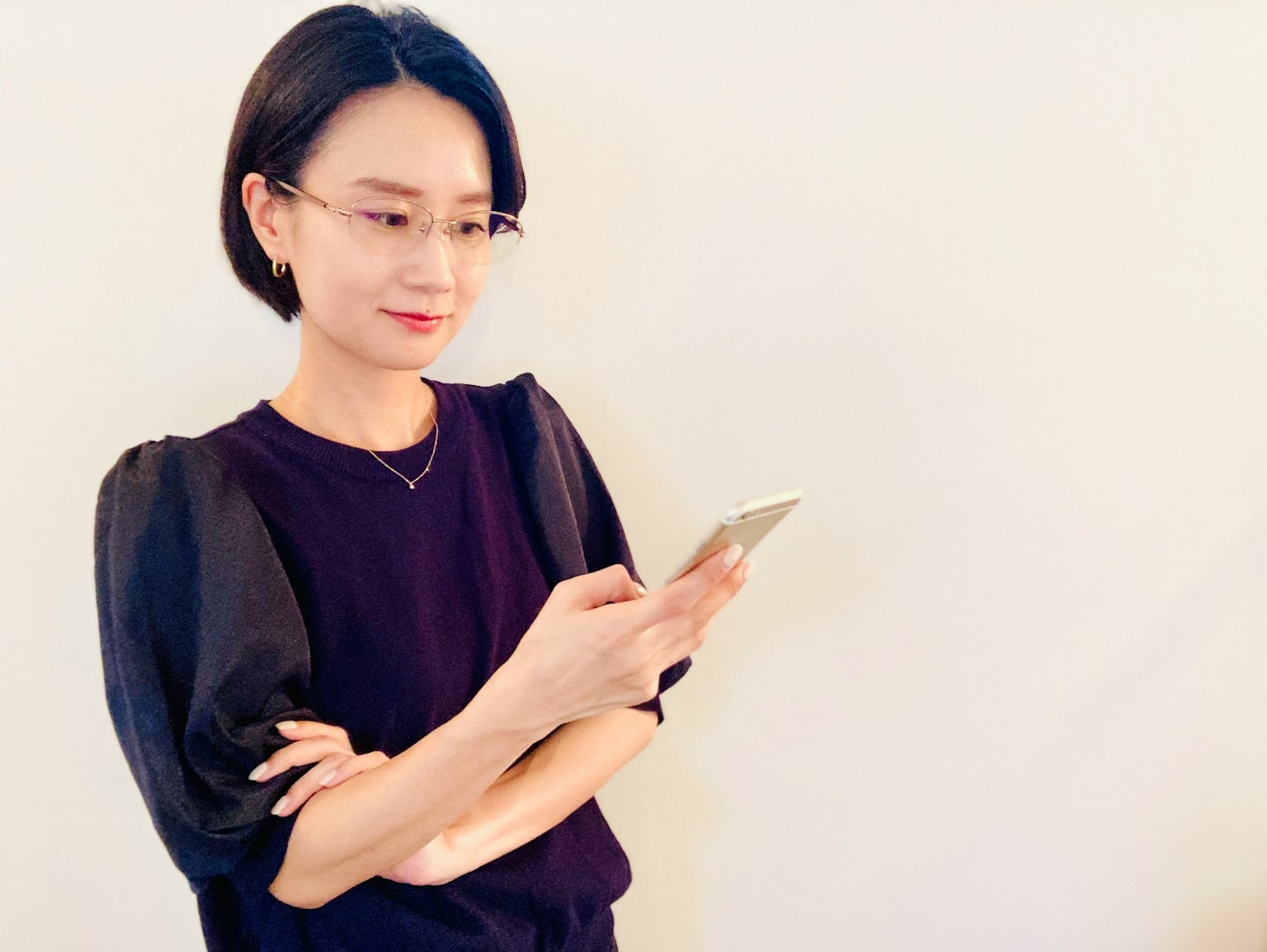 여자가 벽 앞에 서서 스마트폰을 들고 있다