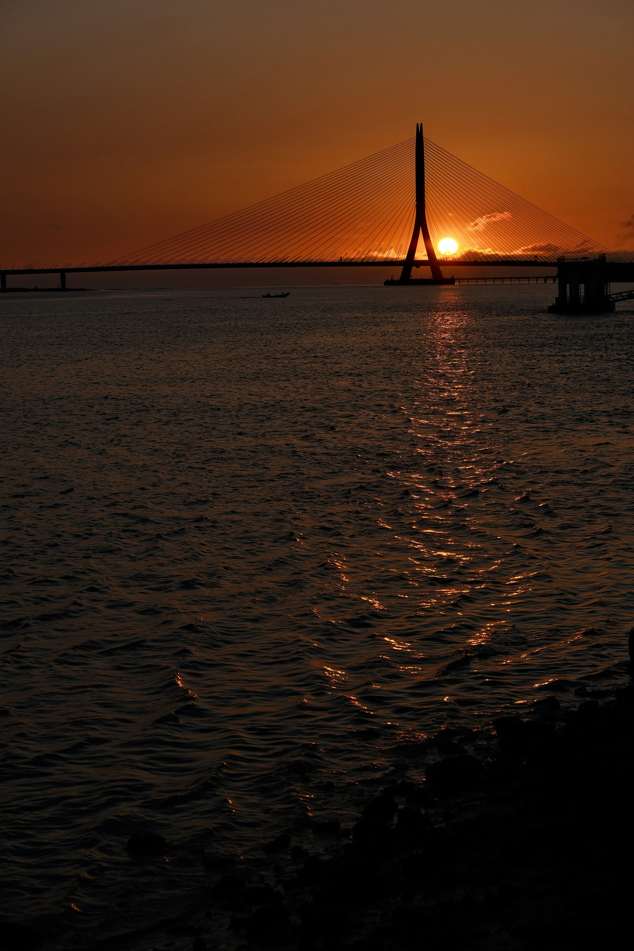 sunset-lit sea with a distant tower silhouette