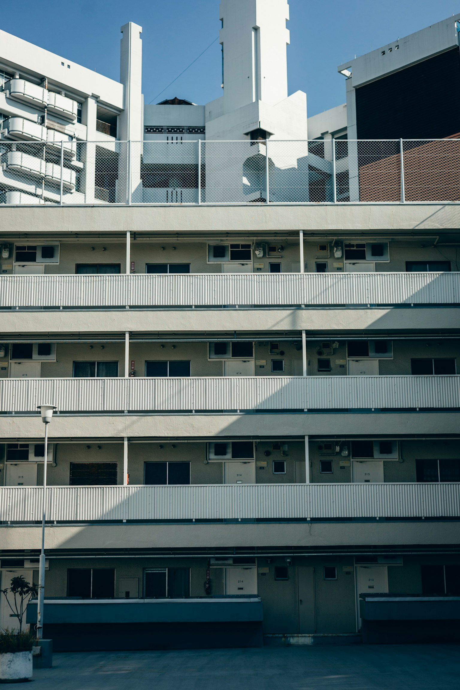 Vue latérale d'un immeuble d'appartements blanc avec plusieurs étages et ciel bleu