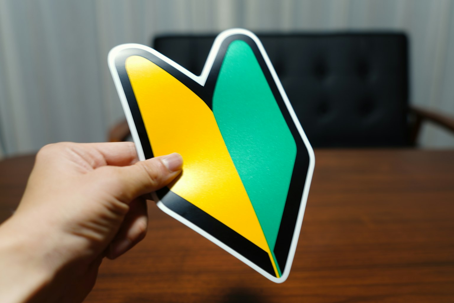 Personne tenant un symbole en forme de cœur vert et jaune sur un fond de table en bois