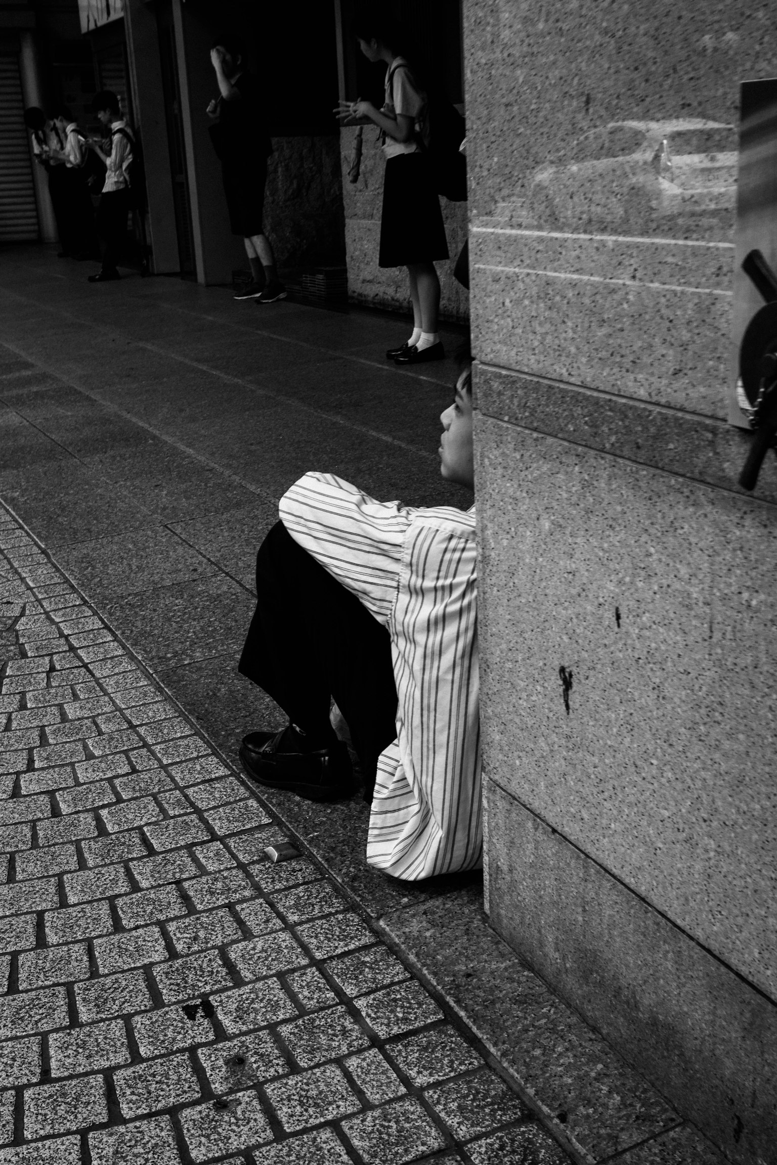 ภาพขาวดำของชายคนหนึ่งพิงกำแพงบนถนน