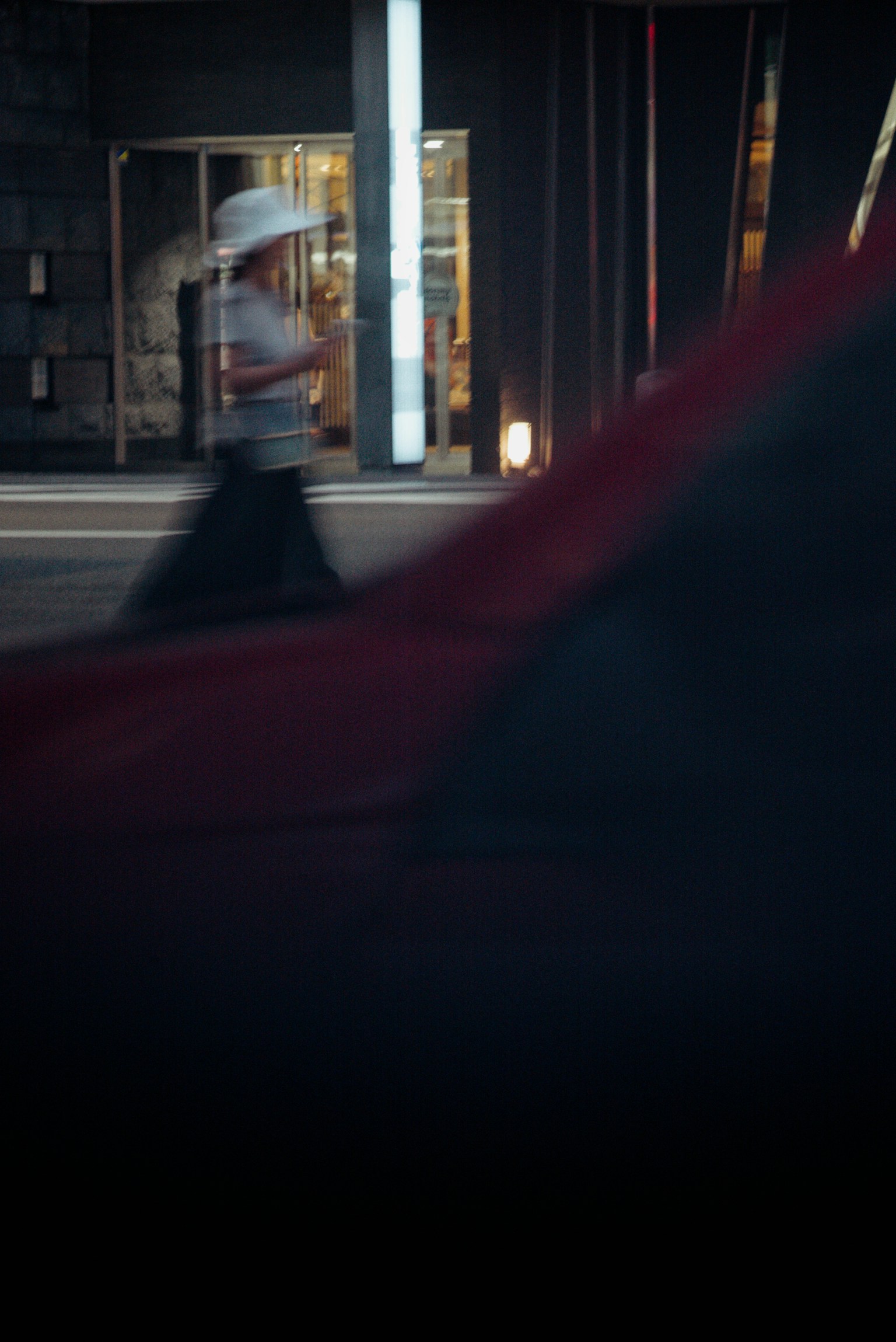 Ein verschwommenes Bild einer Frau, die vor einem roten Auto in einer städtischen Umgebung geht