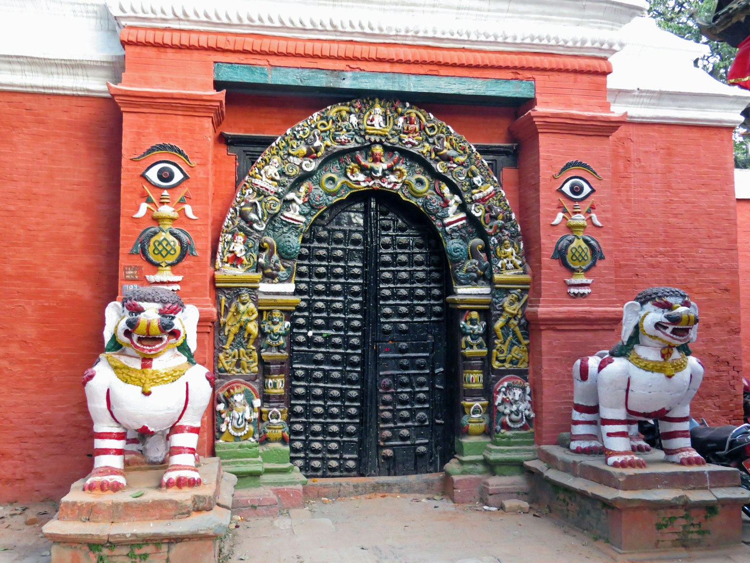 Decorative archway of a temple with red walls and lion sculptures