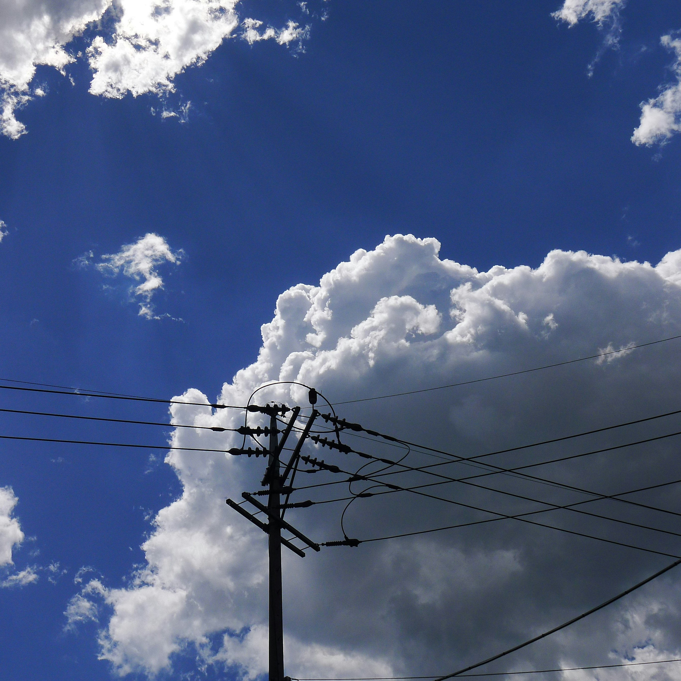 Large clouds over a blue sky with overhead power lines