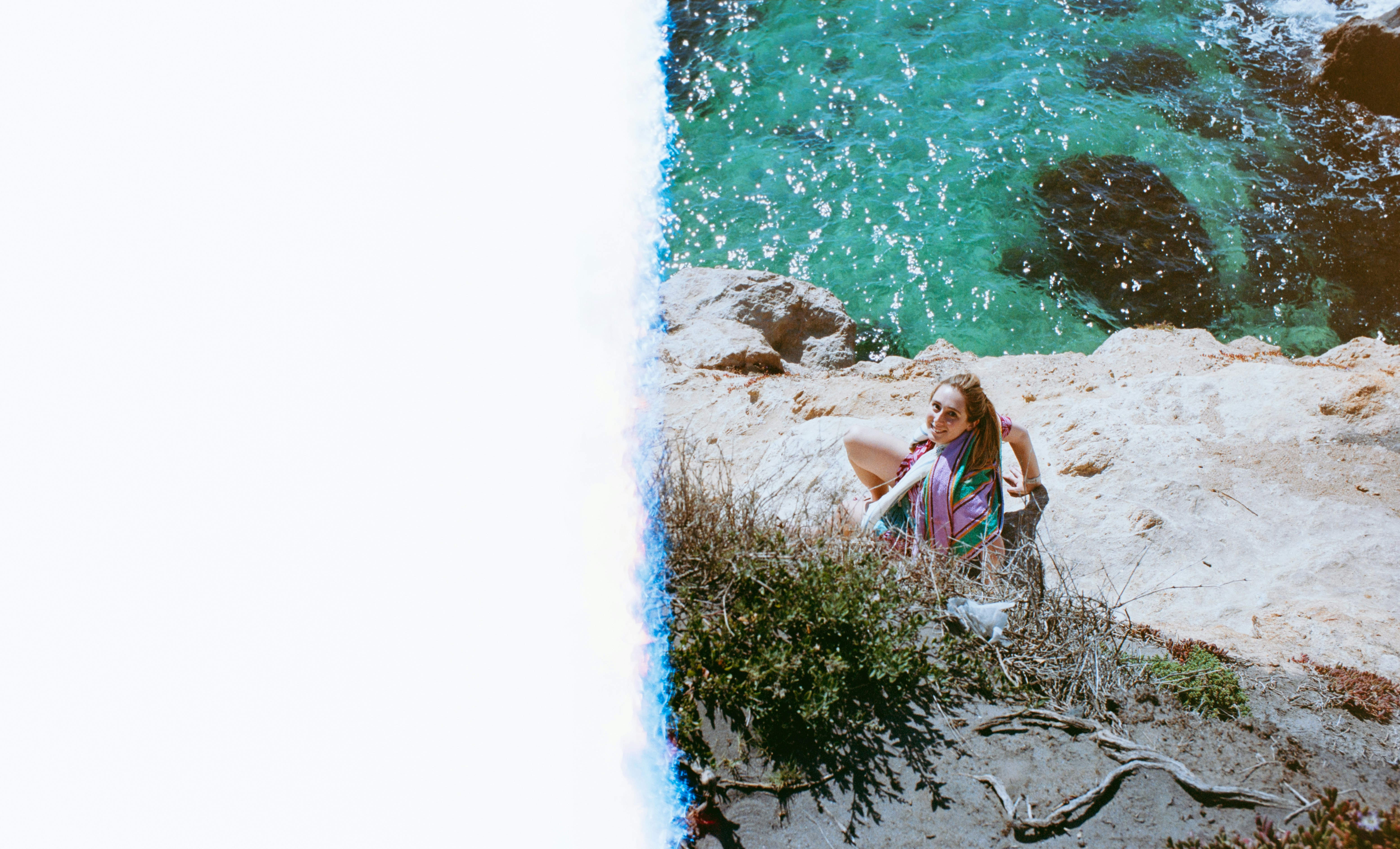 child playing by a rocky shoreline with sun reflections