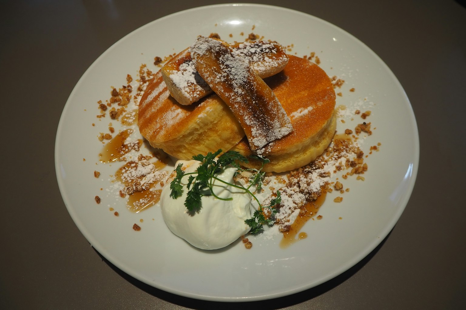 Fluffige Pfannkuchen mit Puderzucker und Fruchtsauce serviert mit Schlagsahne