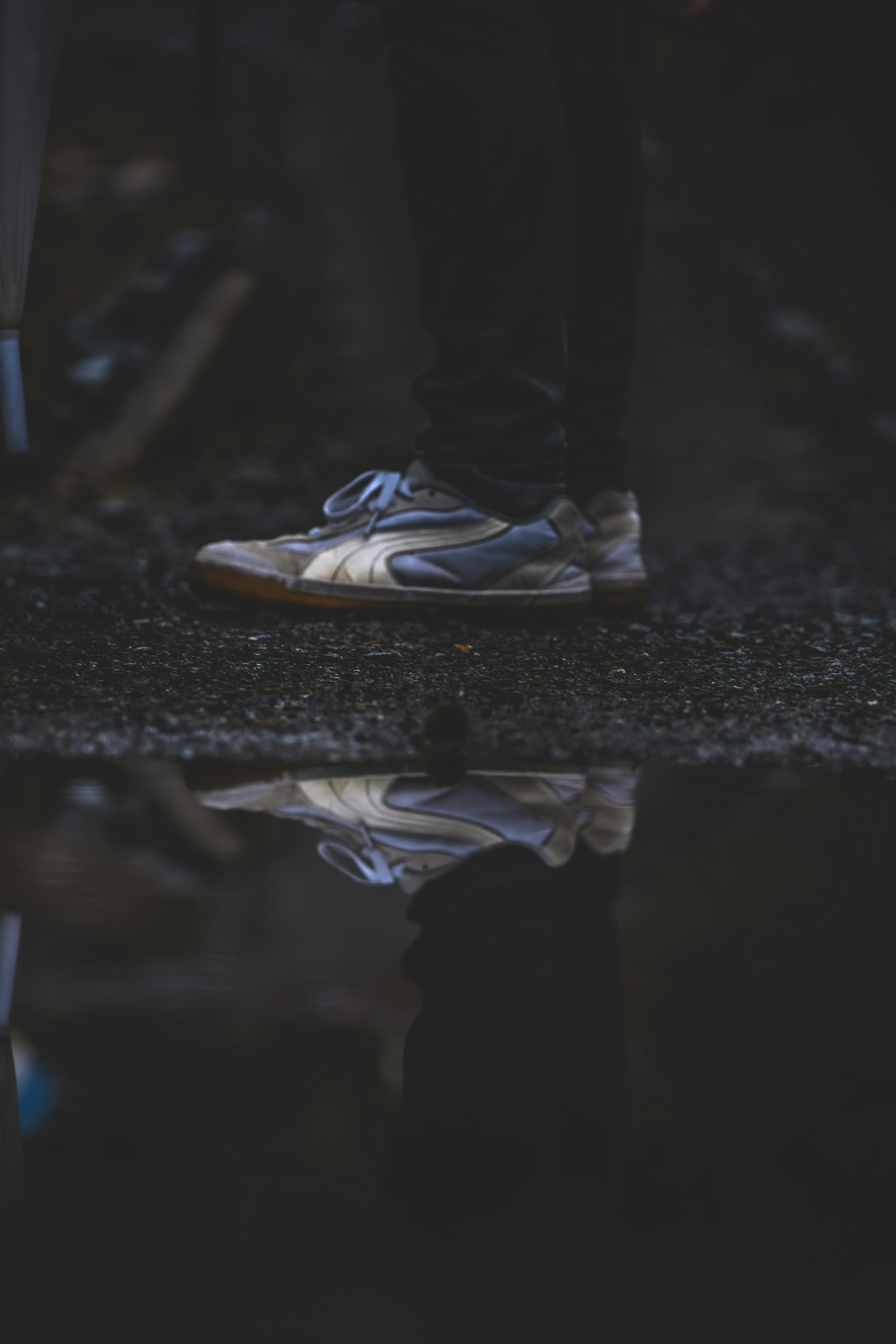 Zapatilla reflejada en un charco con fondo oscuro