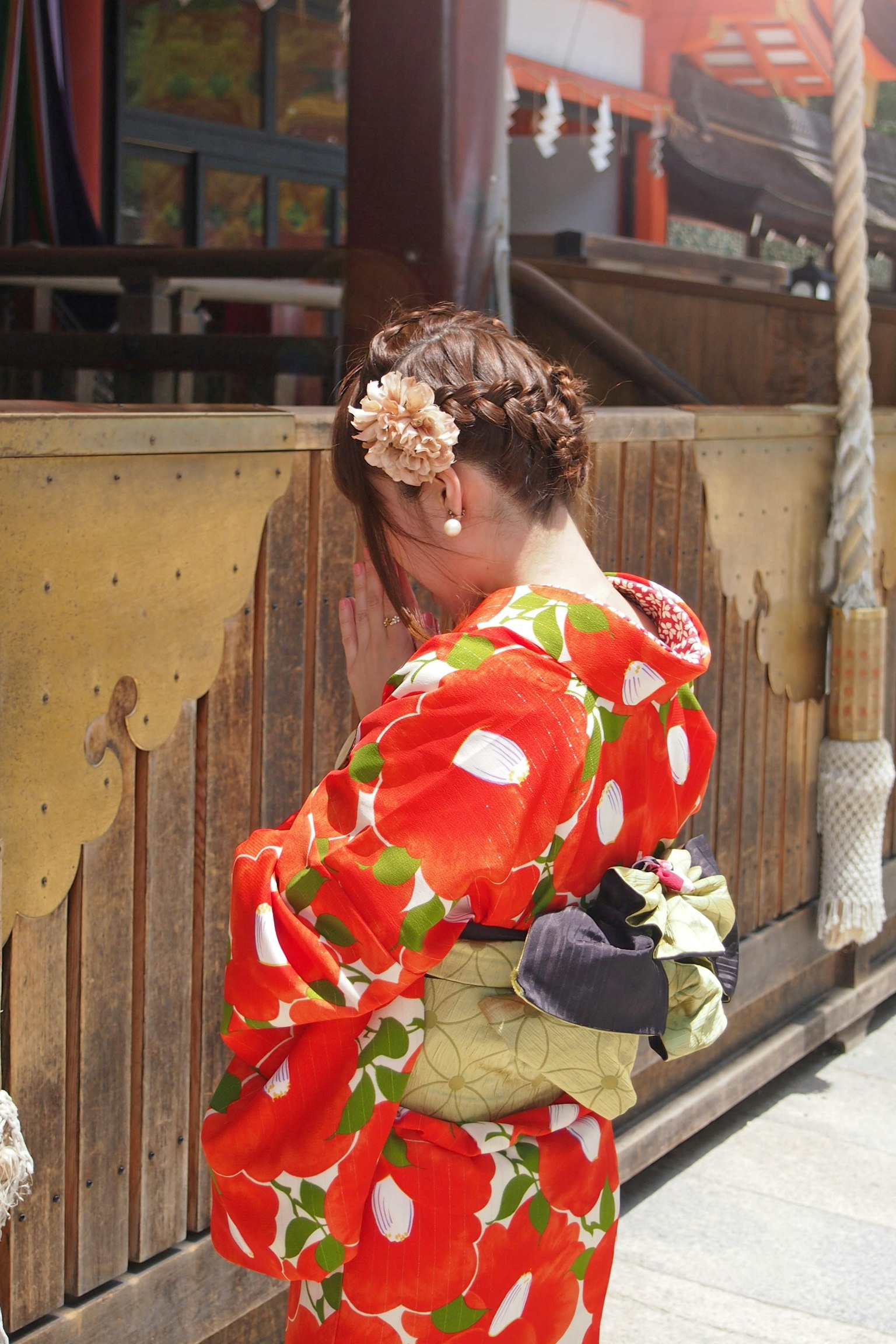 Frau in rotem Blumenkimono, die ihr Gesicht versteckt