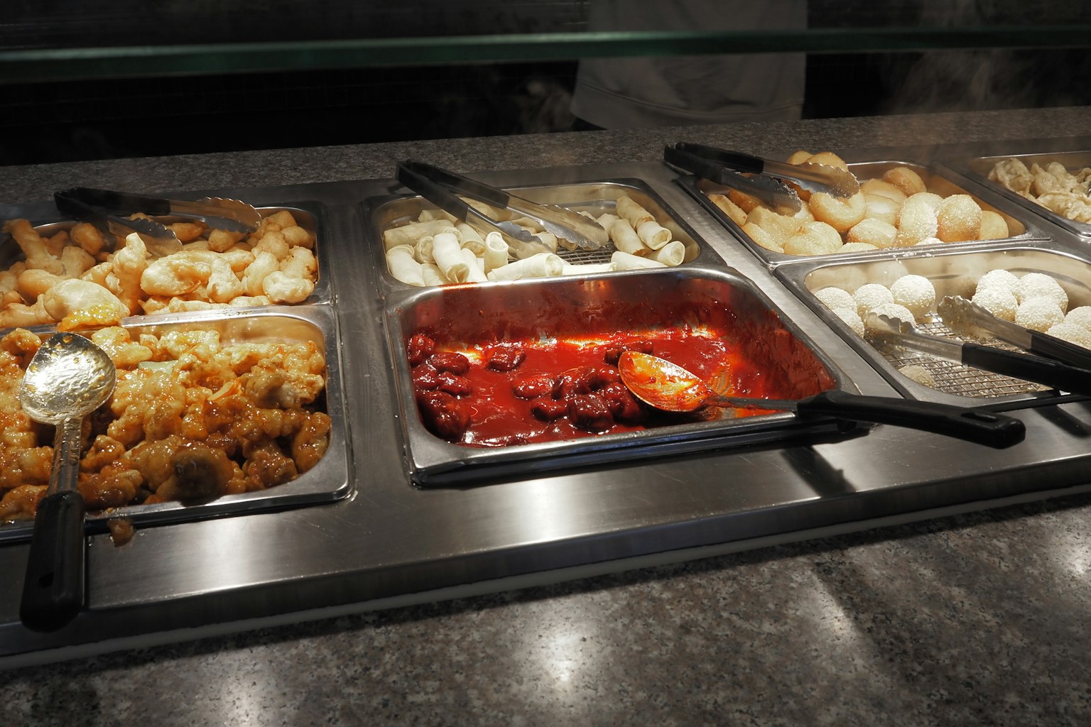 Meja buffet dengan berbagai hidangan dan nampan saus merah di tengah