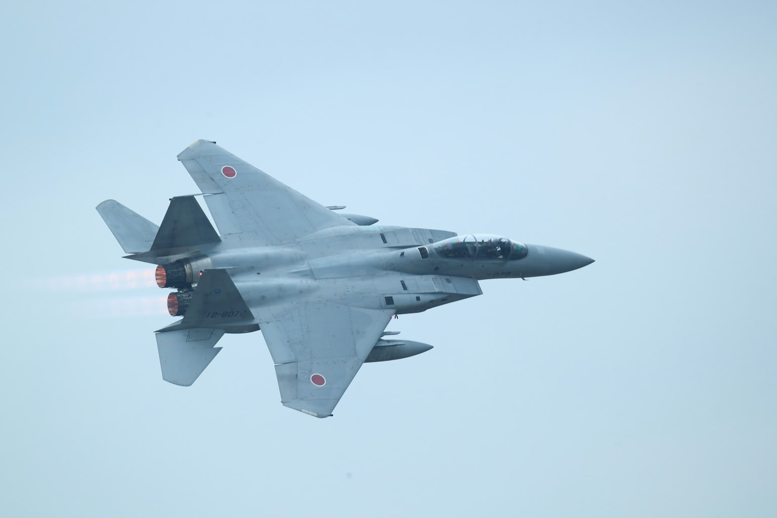 Caza F-15 japonés volando en el cielo con humo saliendo de los motores