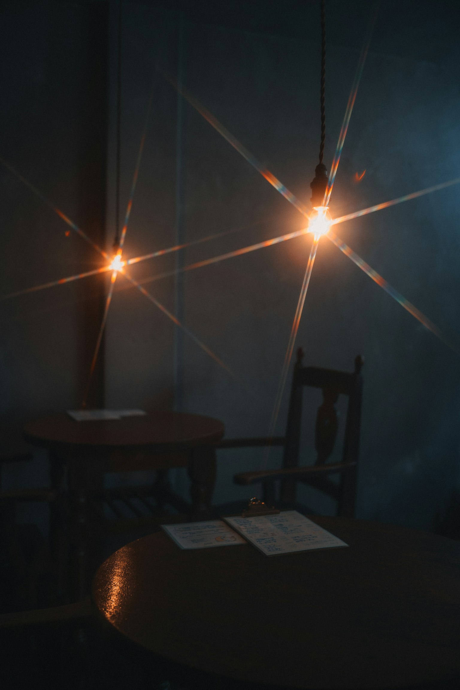 Ruang redup dengan lampu gantung dan meja kayu