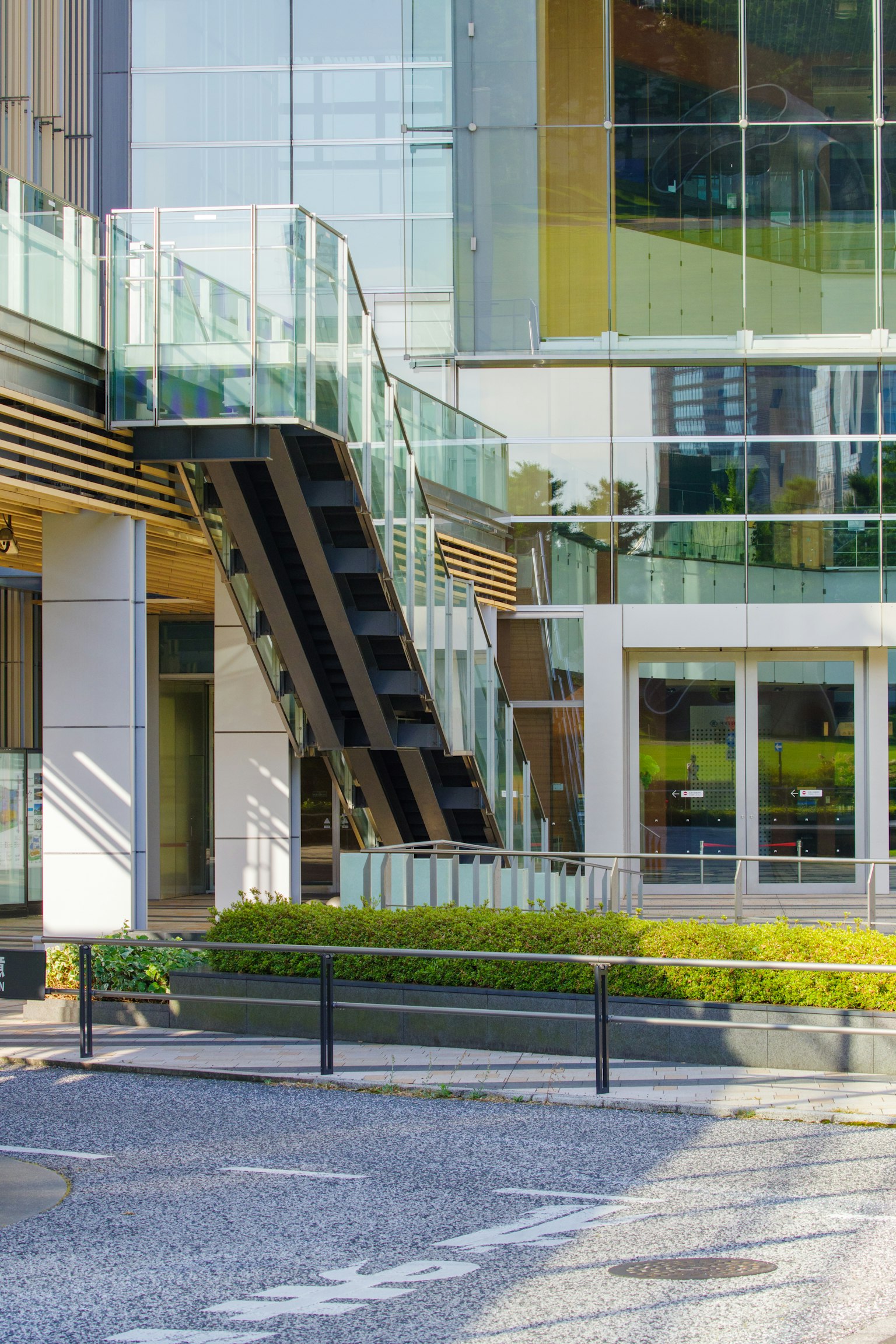 Bâtiment moderne avec escalier en verre et aménagement paysager vert