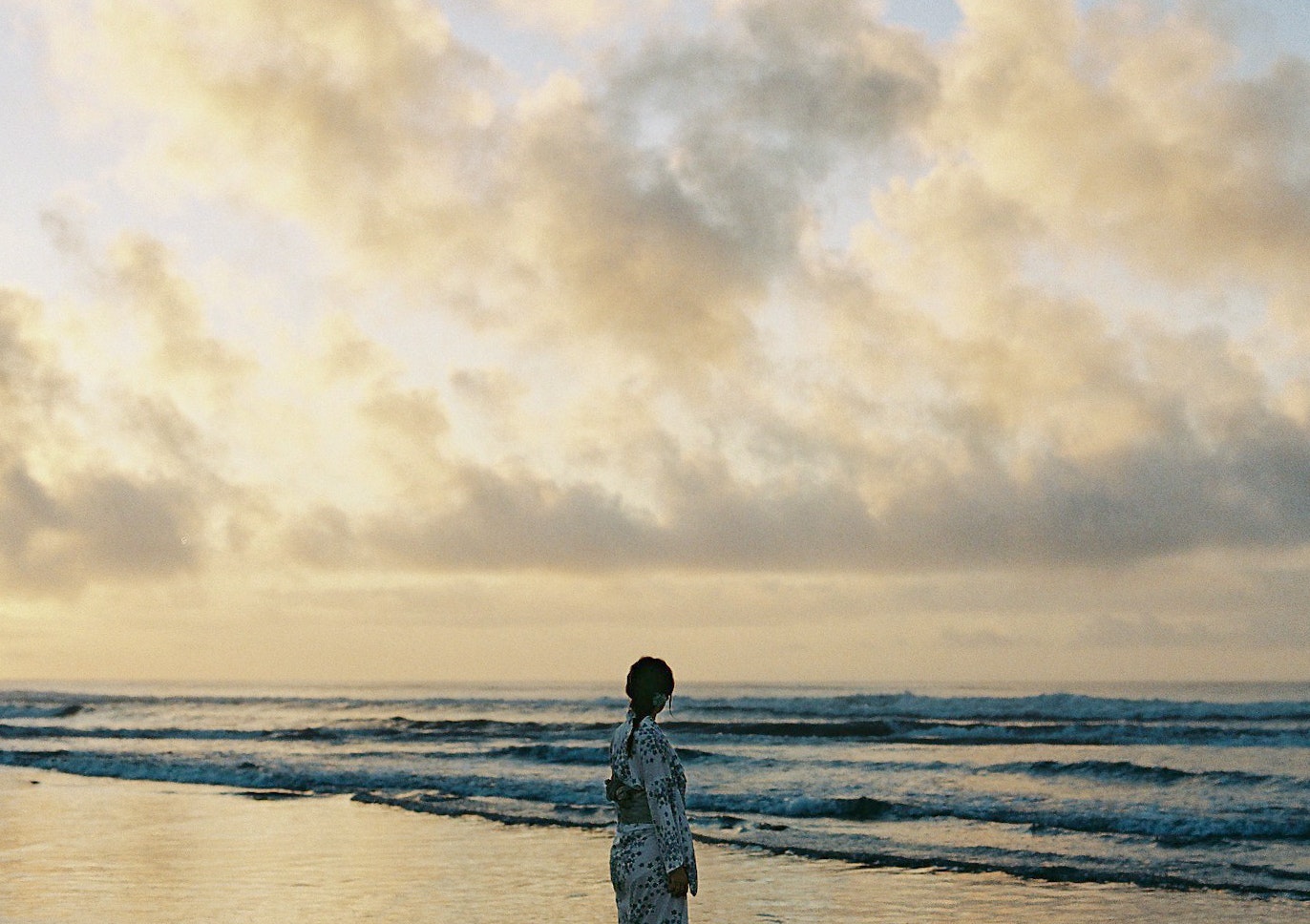 雲の広がる海辺で立つ人物