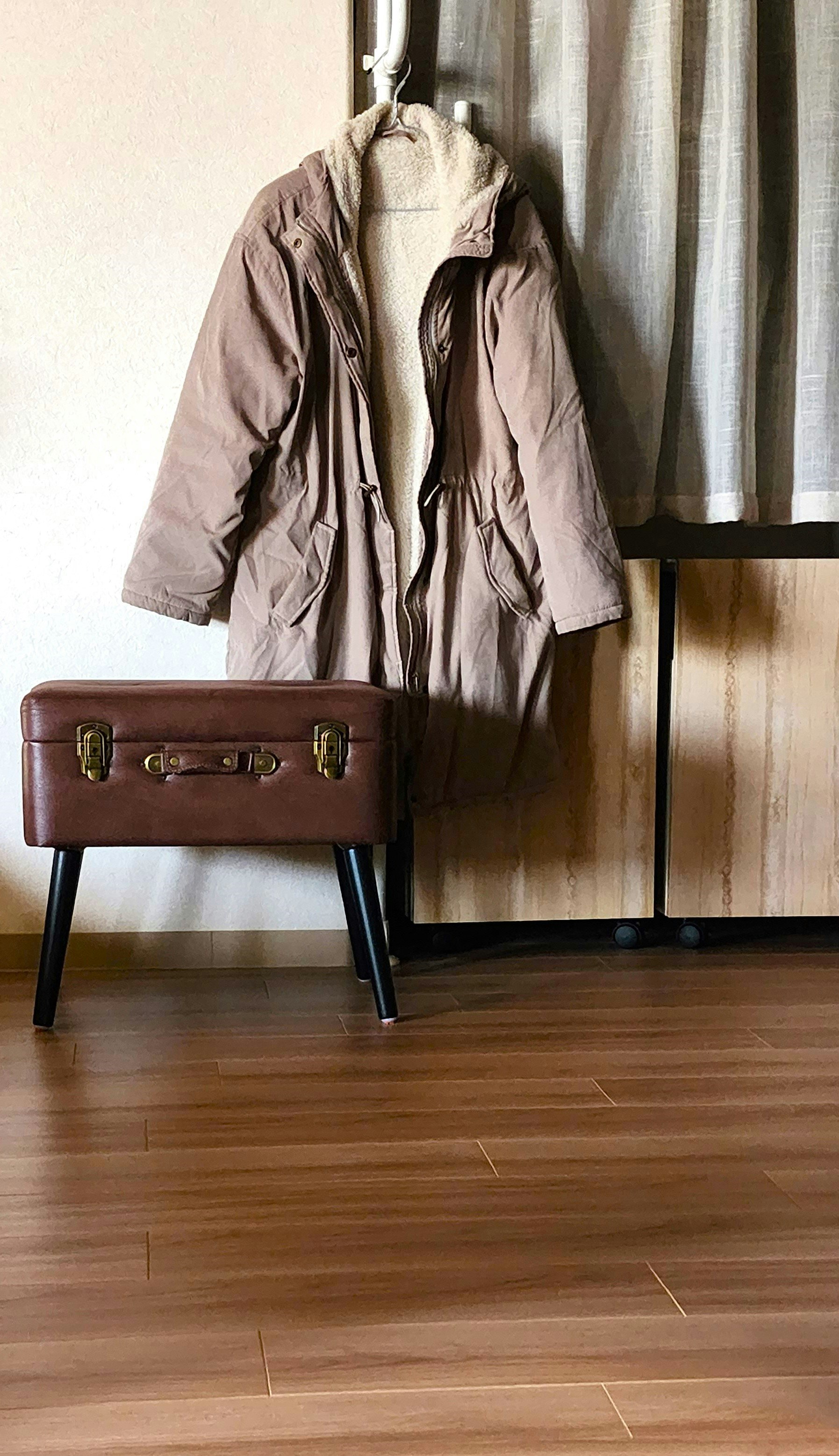 jaket krem di kursi dengan tas kulit di dalam ruangan