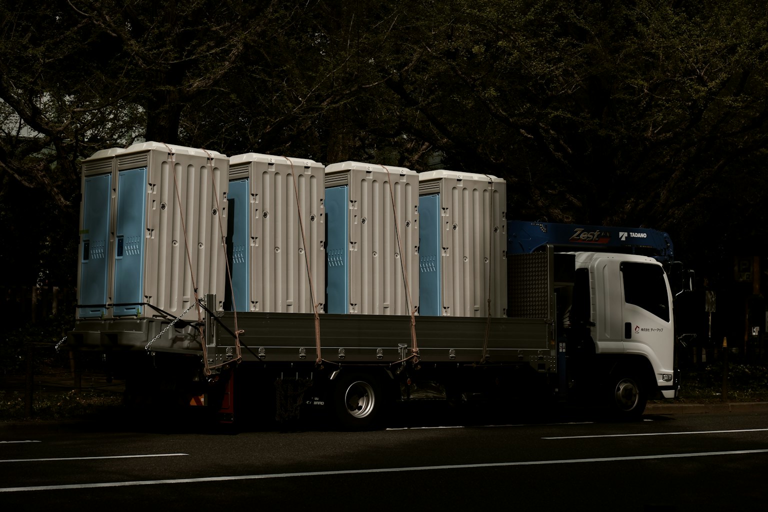 Un camión que transporta baños portátiles estacionado en la calle