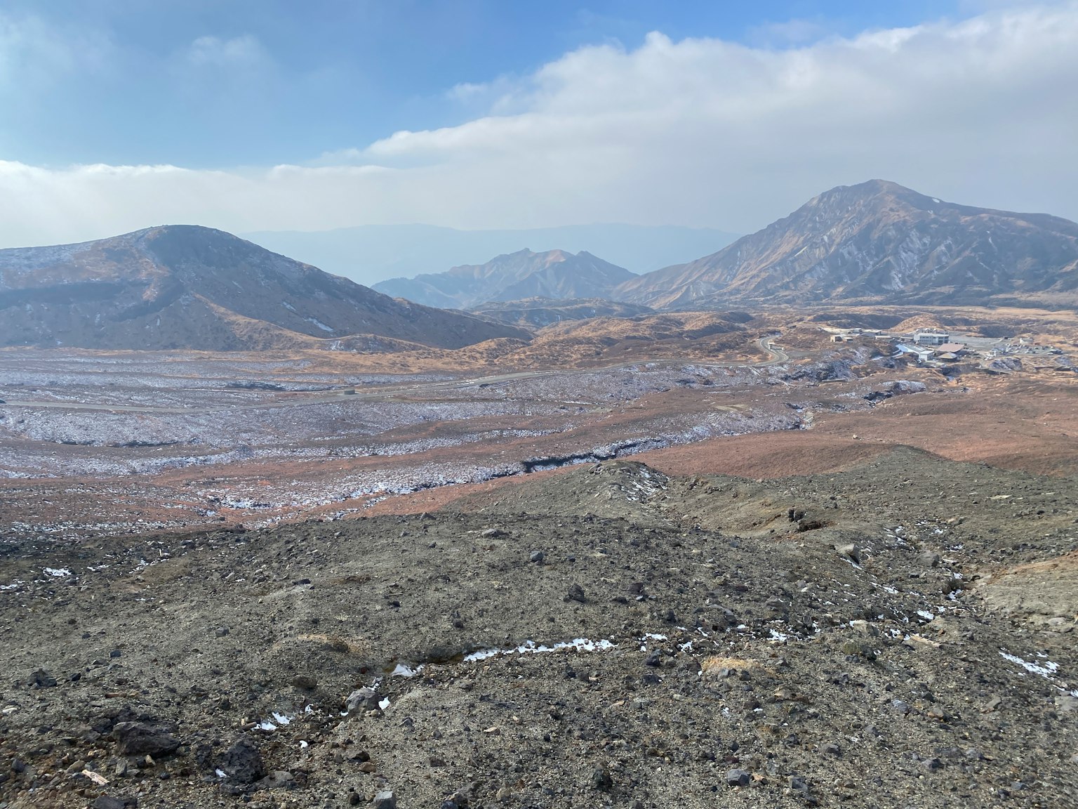 Pemandangan vulkanik dengan medan berbatu dan gunung jauh