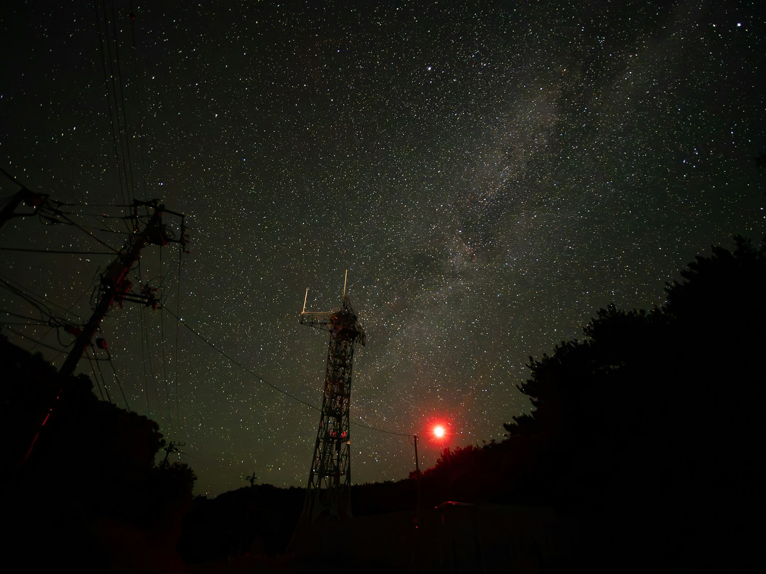 Ciel nocturne étoilé avec une tour de communication et une lumière rouge