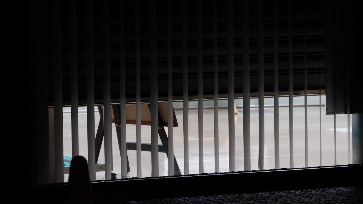 A view through blinds showing a chair and wet floor