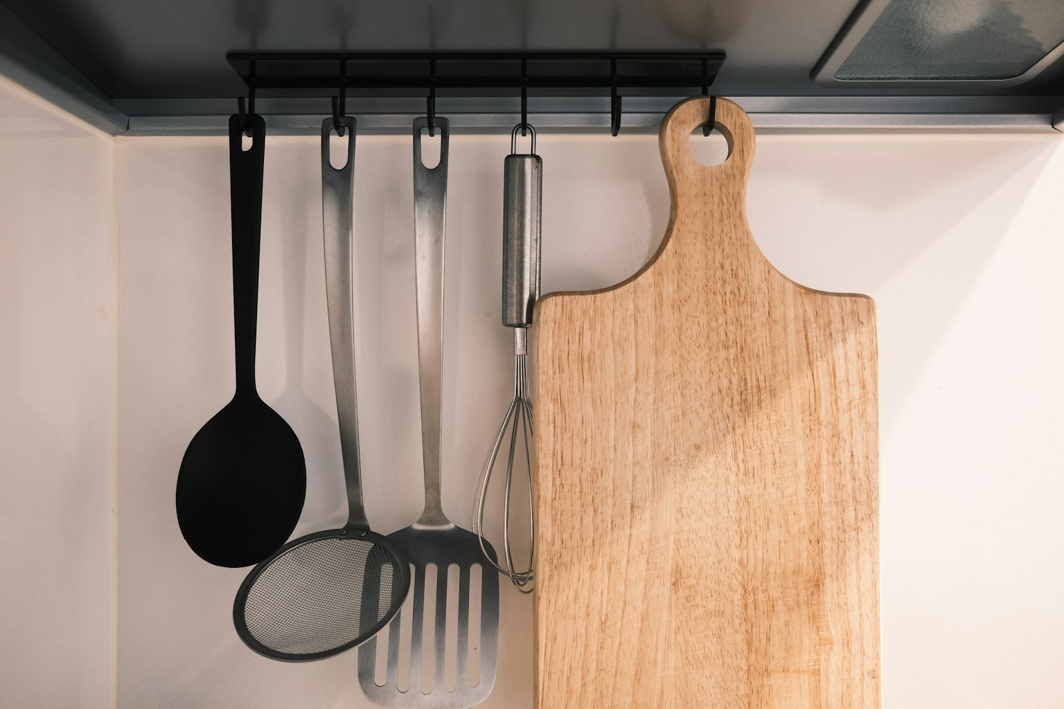 Utensili da cucina appesi e un tagliere in legno sulla parete