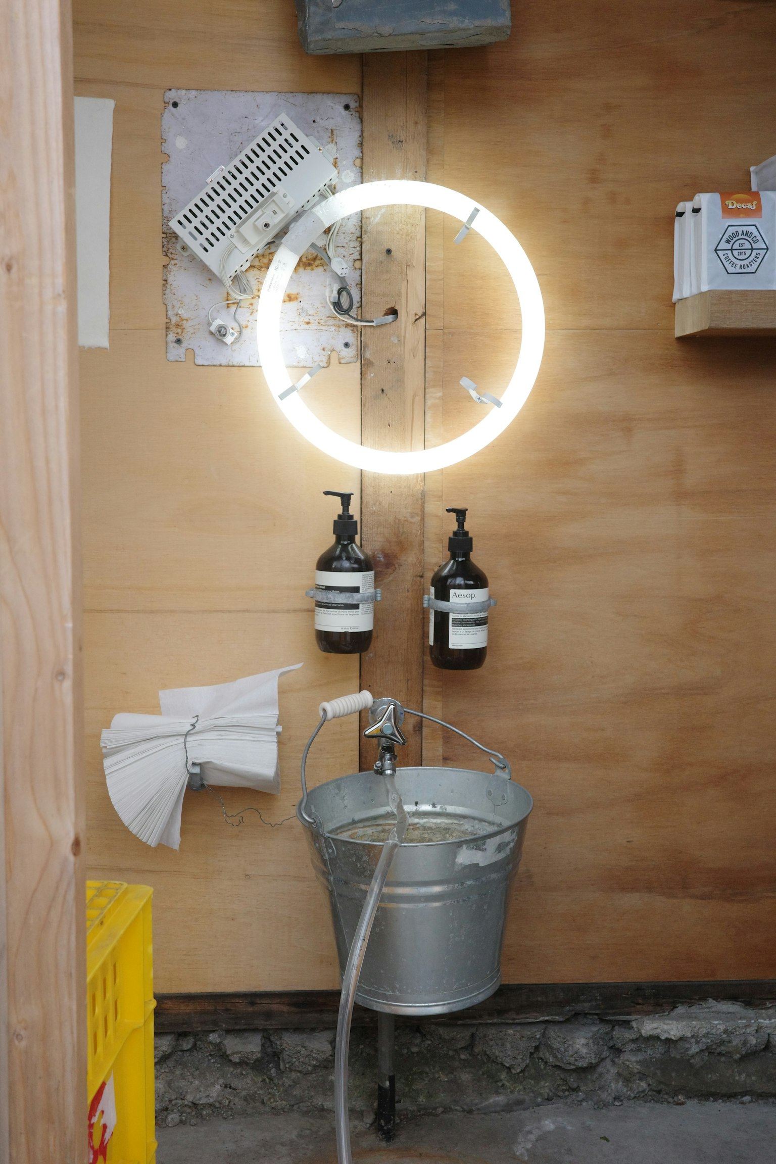 Un éclairage néon circulaire monté sur un mur en bois avec des flacons de shampooing dans une zone de lavage