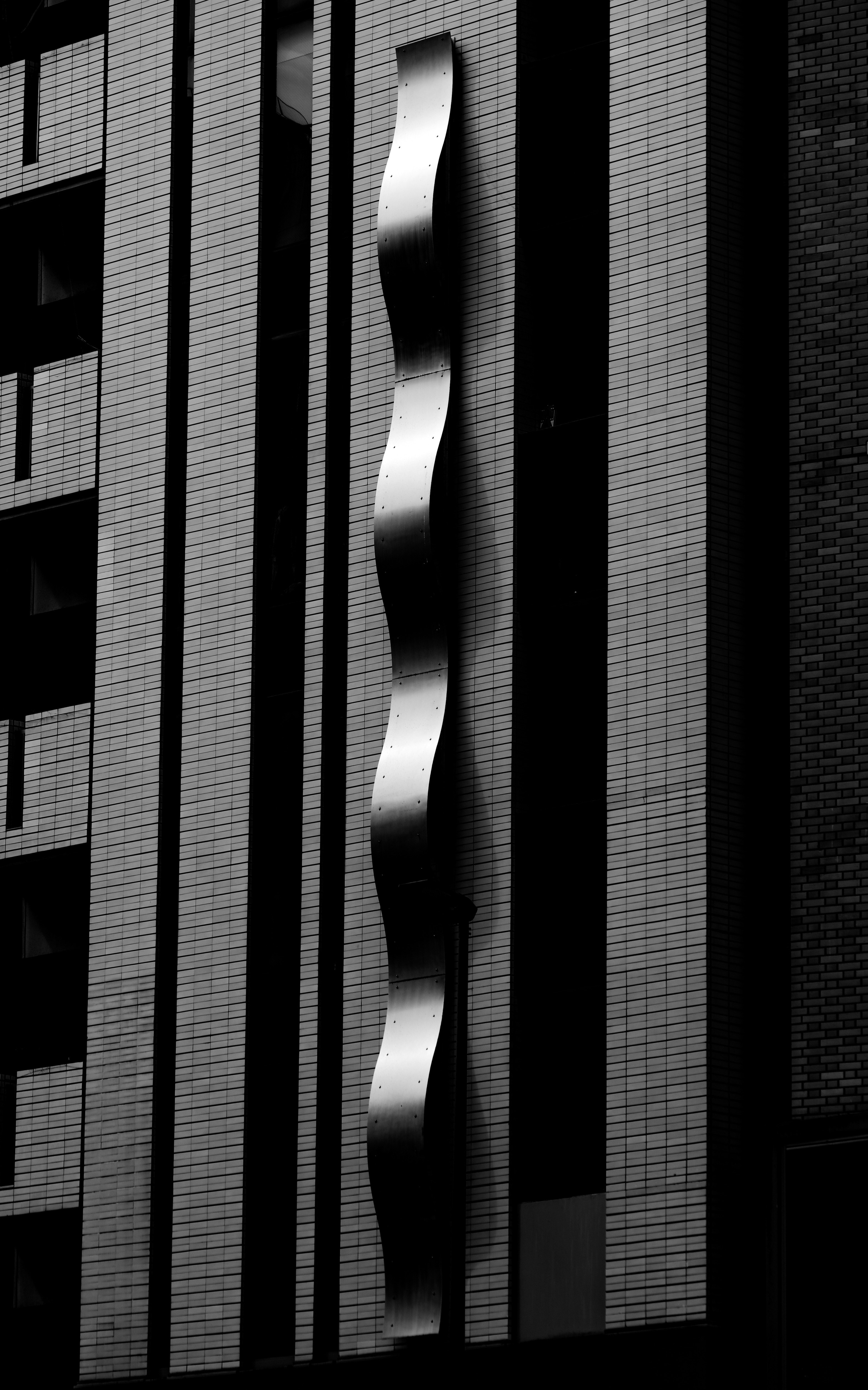 建物の外壁に並ぶ縦の窓と影のある都市景観