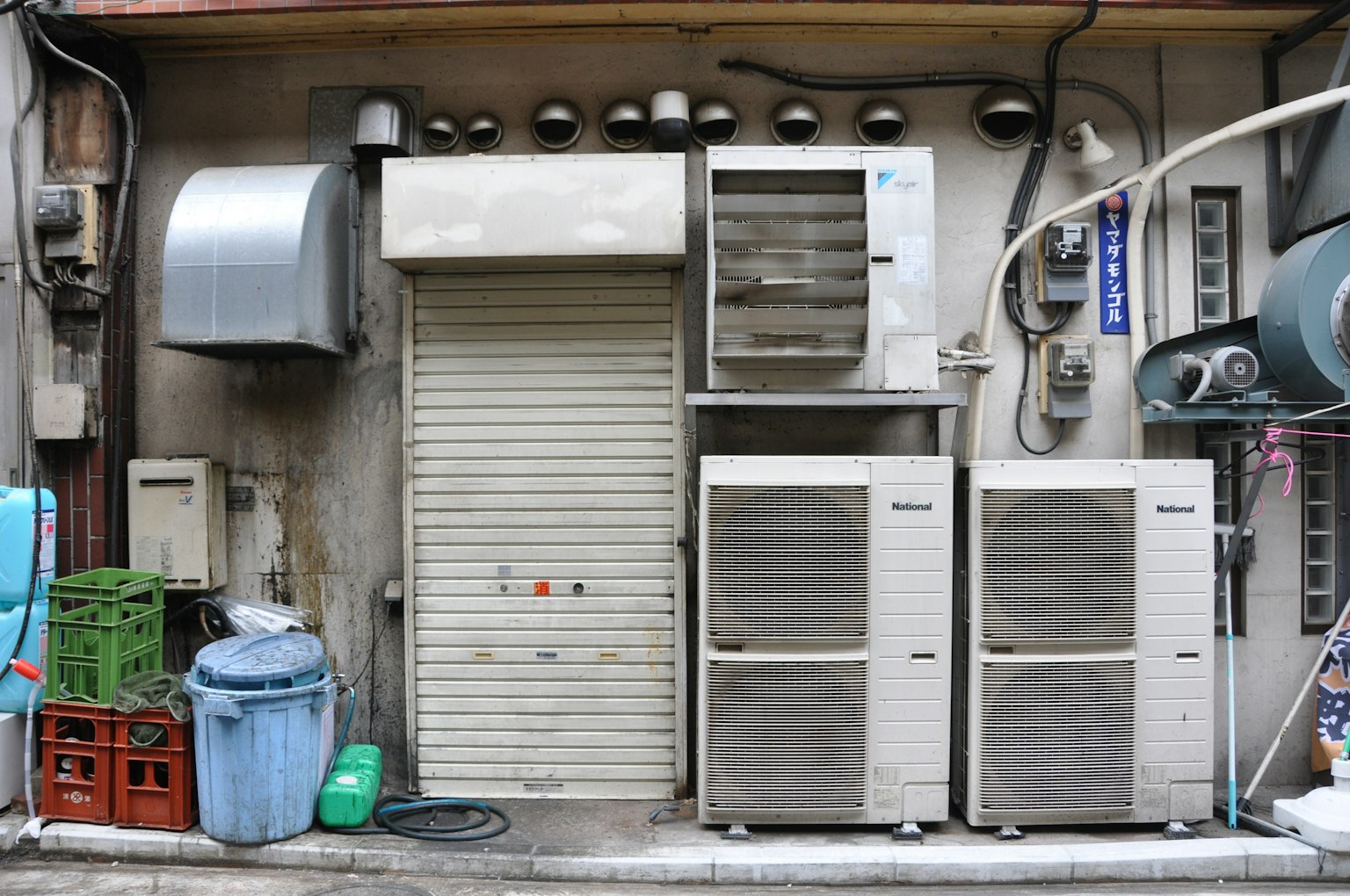 Exterior wall featuring air conditioning units and metal vents