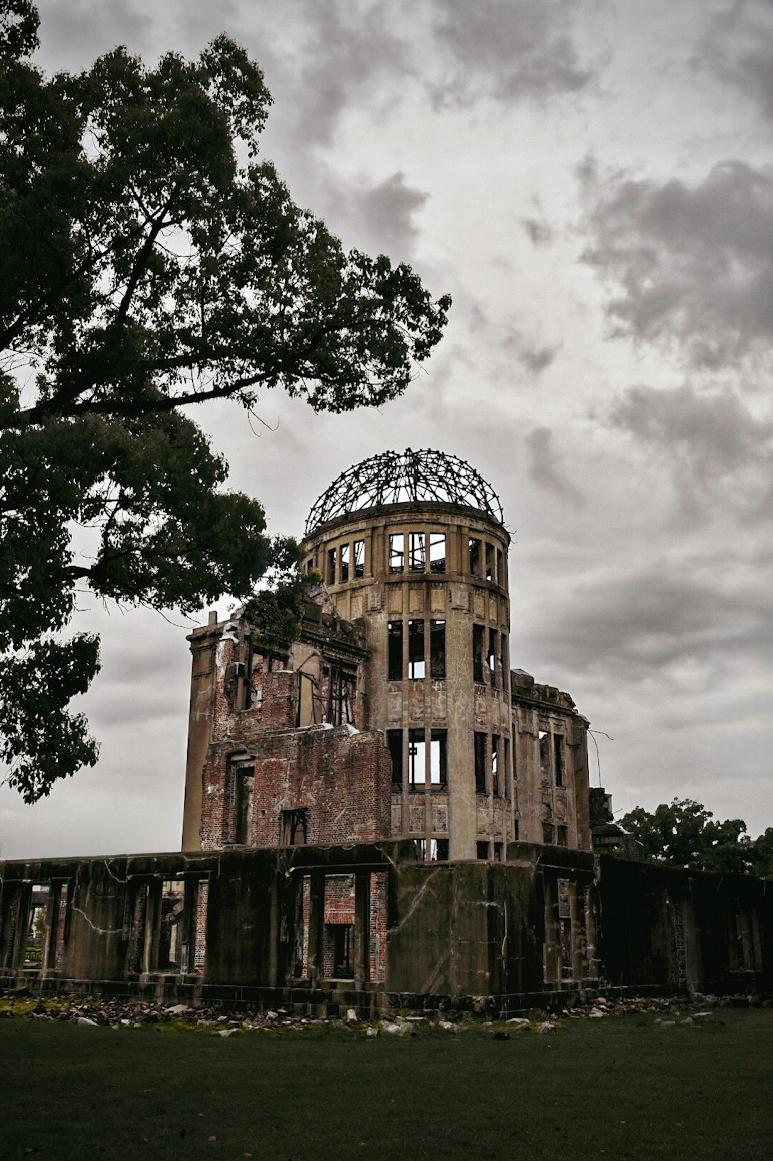 Hiroshima Peace Memorial, historic ruin, cloudy sky, surrounding greenery, damaged structure