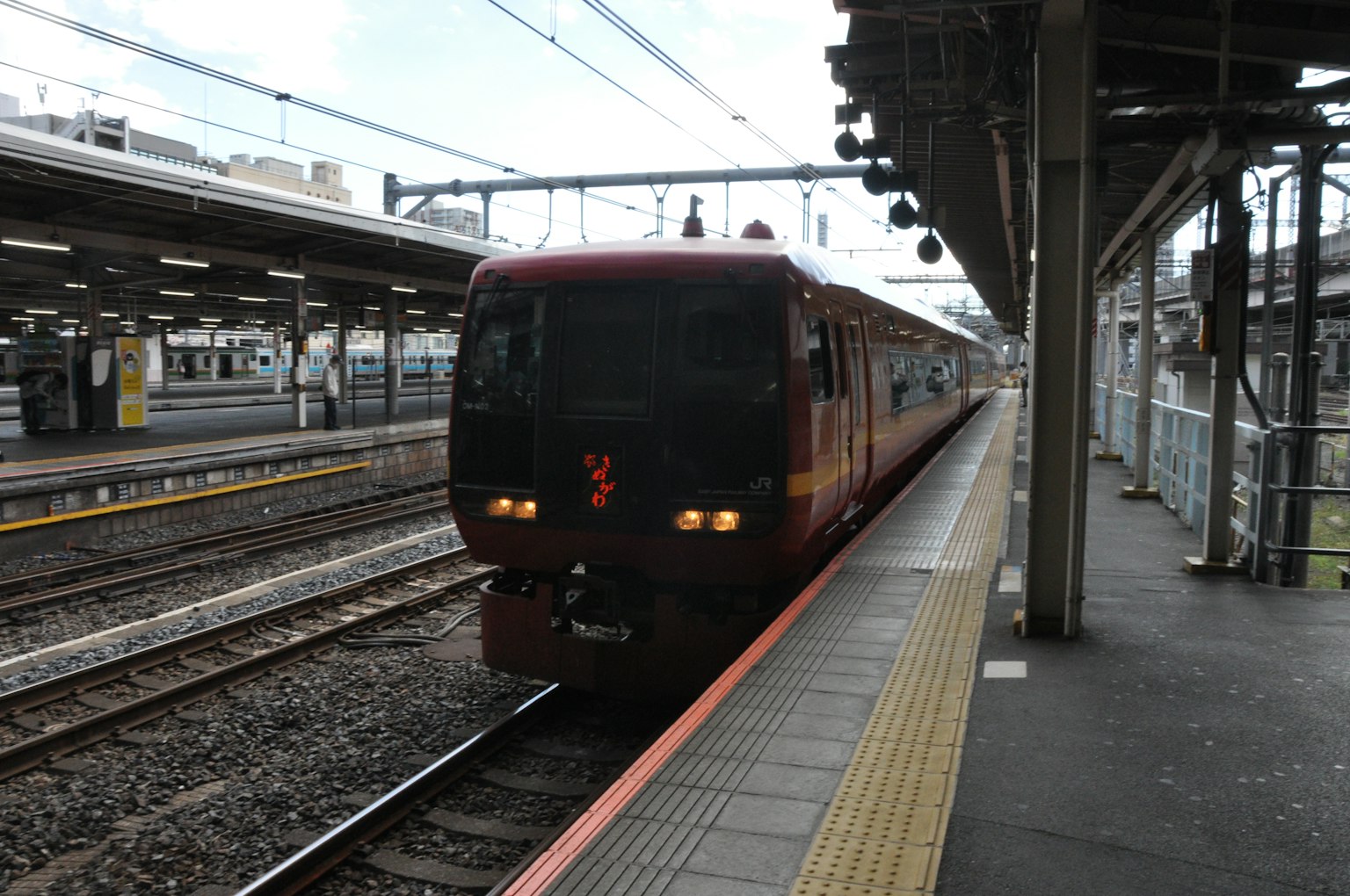 Kereta merah tiba di stasiun dengan peron dan rel