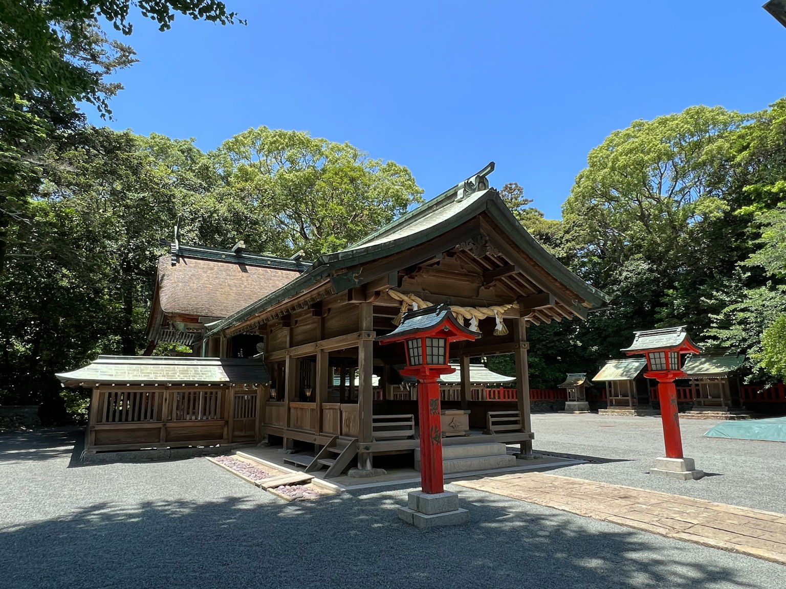Traditional shrine building surrounded by green trees and red torii gates
