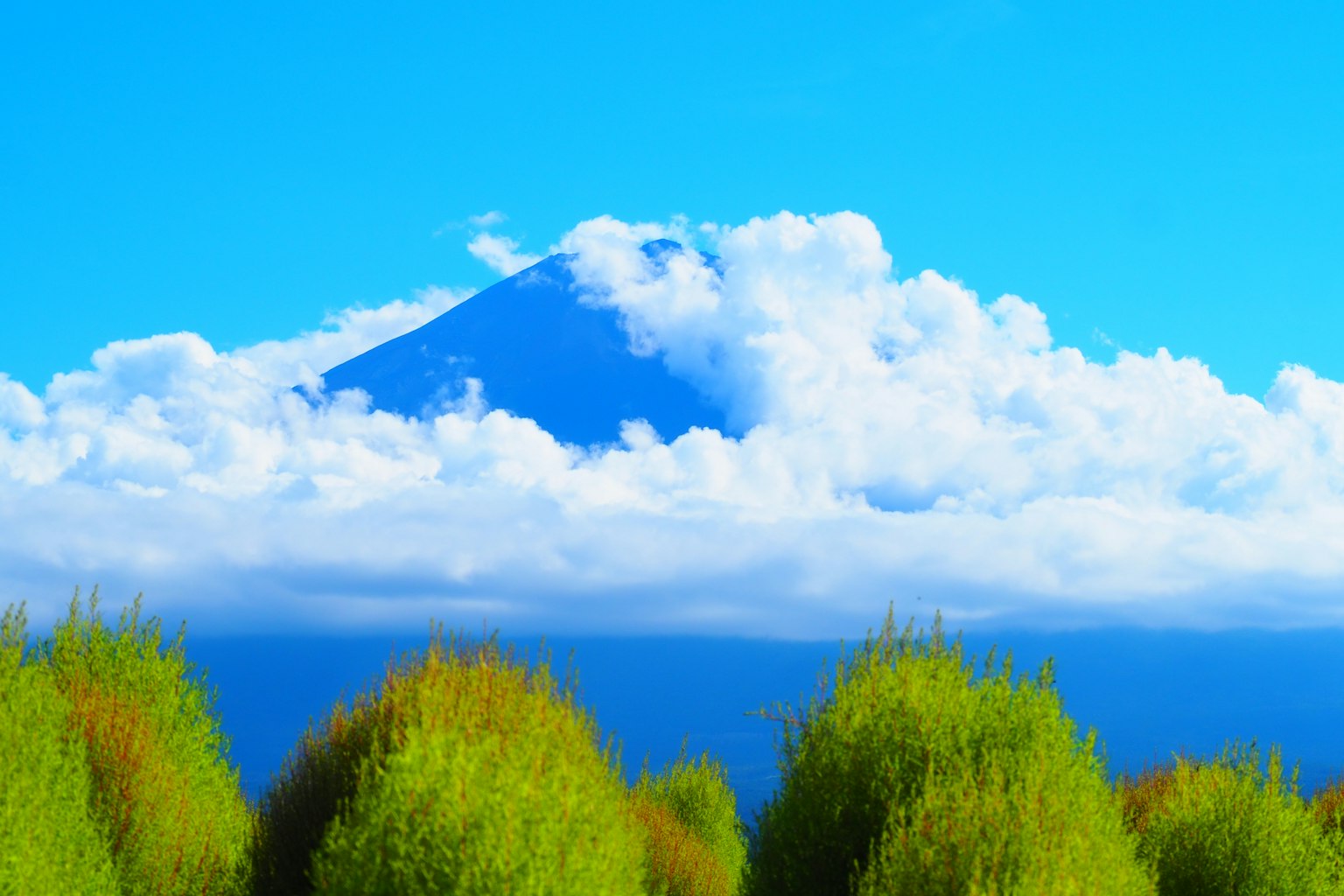 A beautiful landscape featuring a mountain surrounded by blue sky and clouds