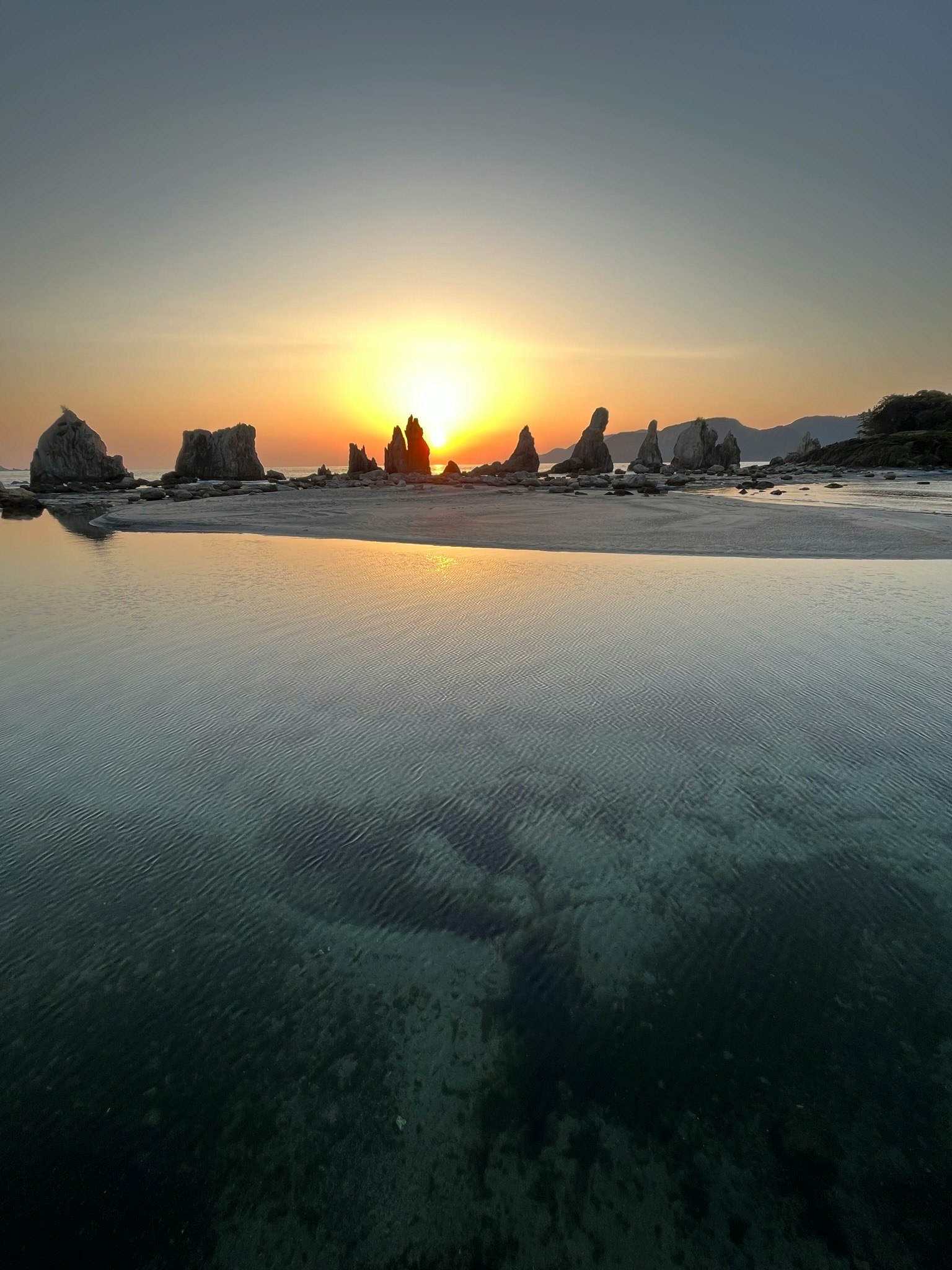 seaside rocks and sandy beach at sunset
